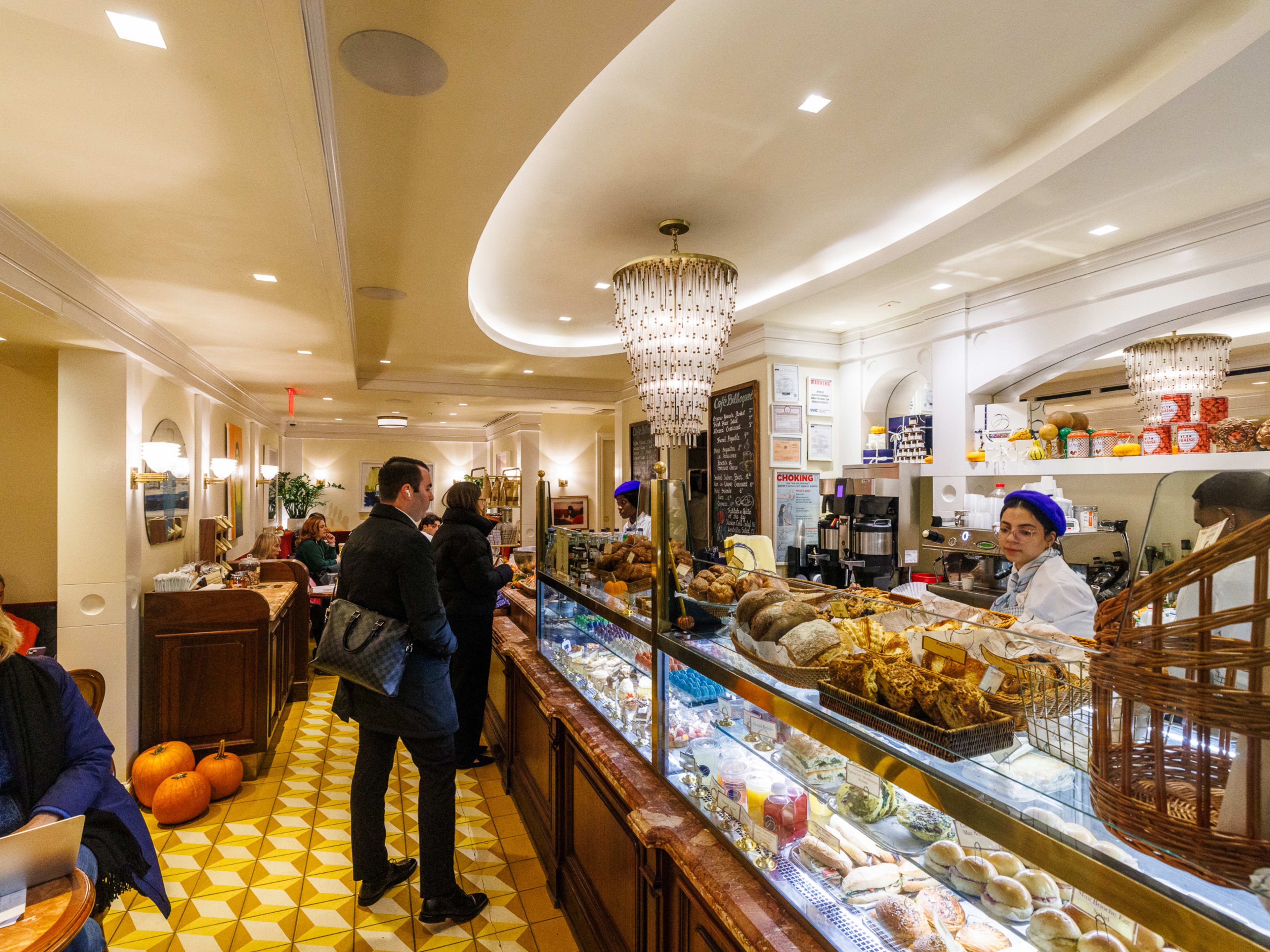 Le Bilboquet interiors with tons of pastries and baked goods on display behind the glass counter and customers in line ordering over the counter