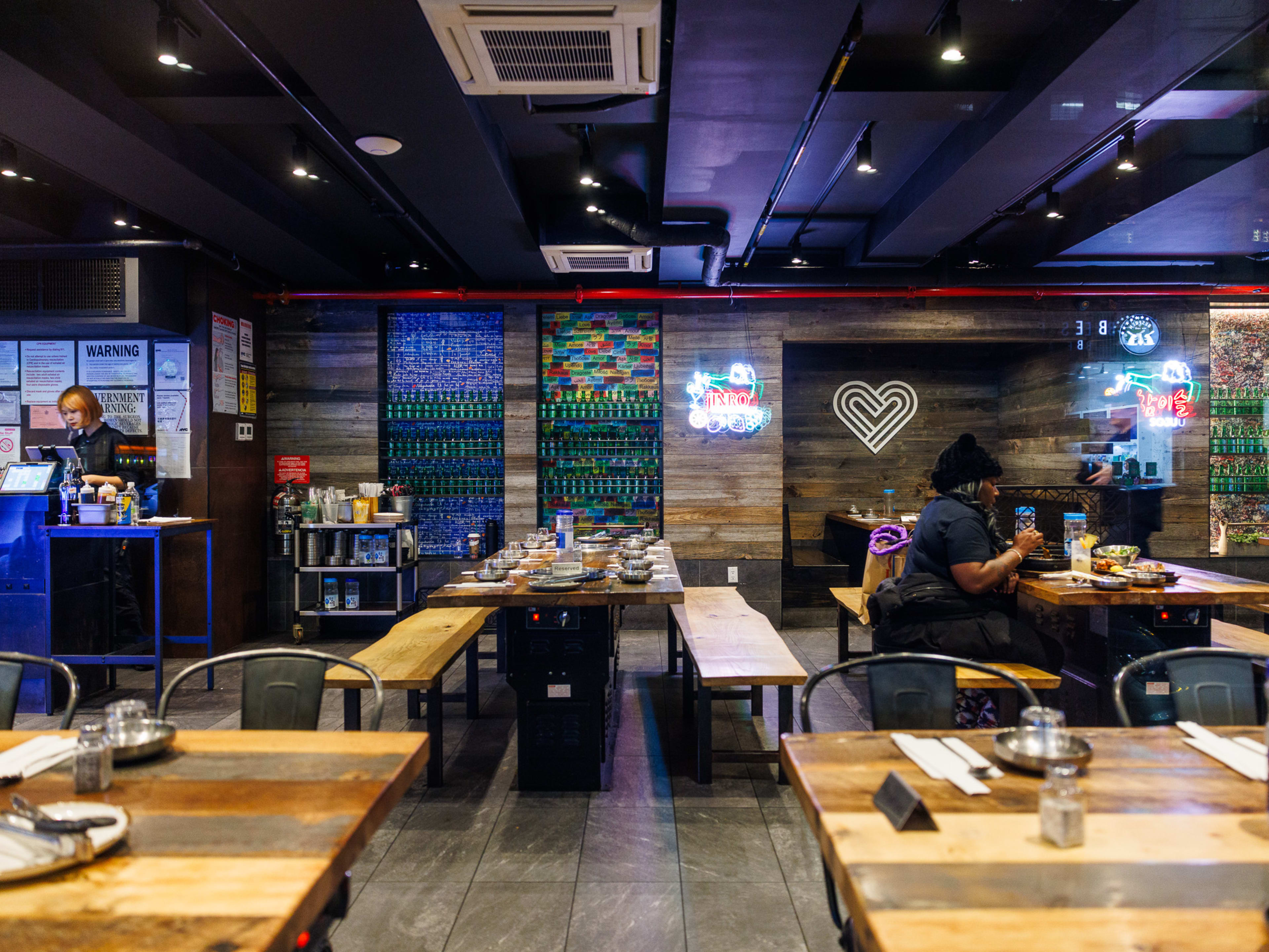 Love Korean BBQ interiors with long wooden tables and neon signs on the back wall