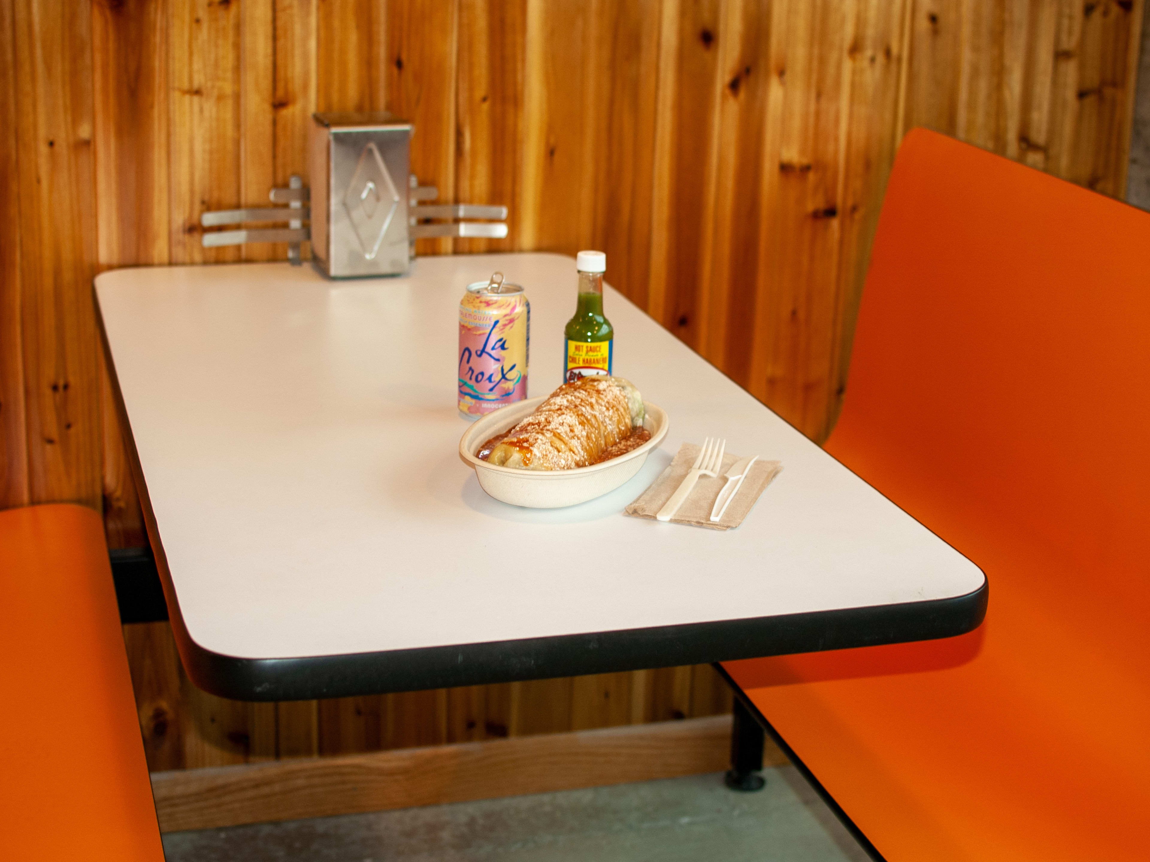 Super Burrito interior with colorful booths, wood paneling, and a burrito on the table