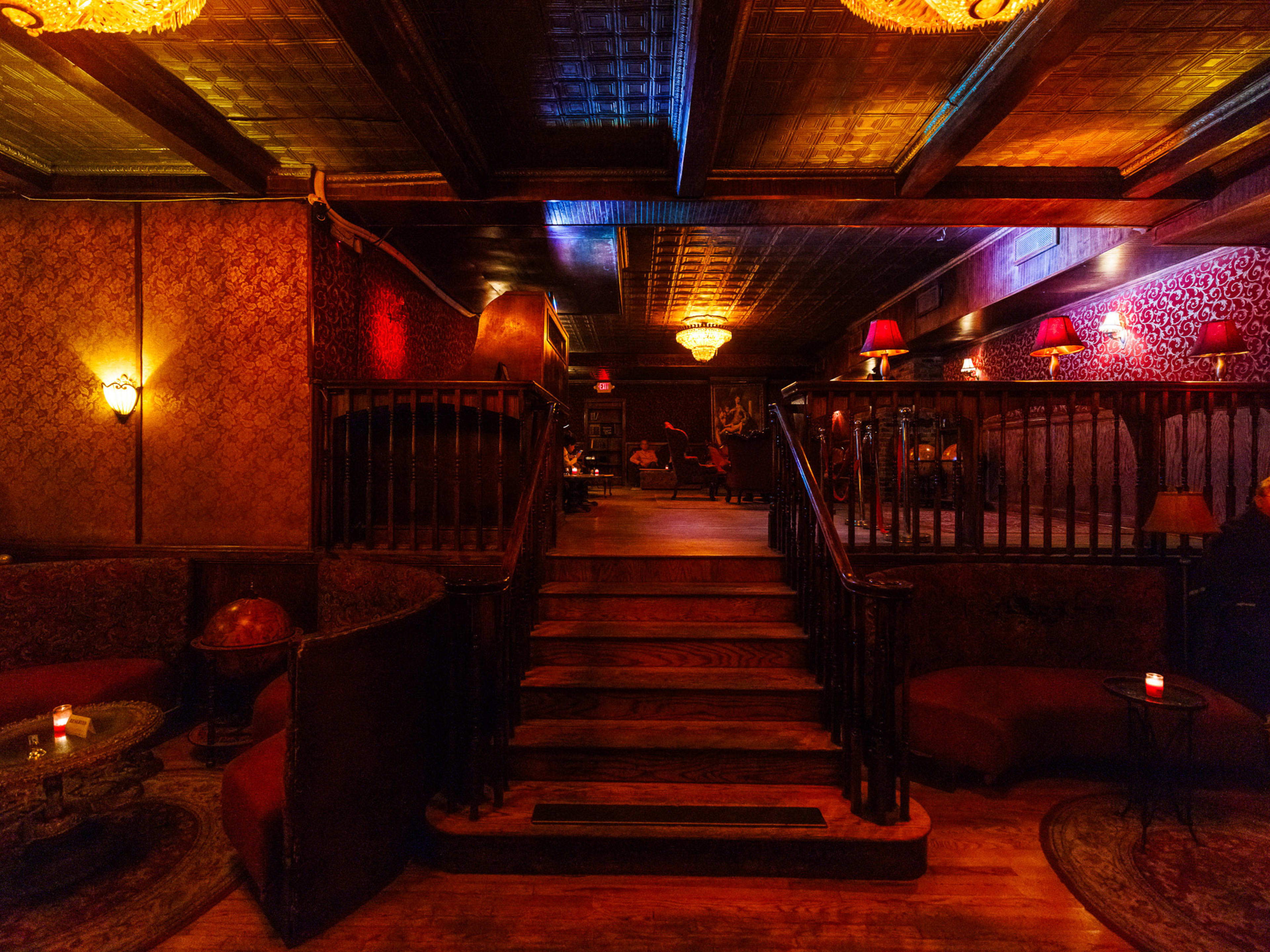 The Back Room speakeasy interiors with dim red lighting and a staircase leading up to a second level of the bar