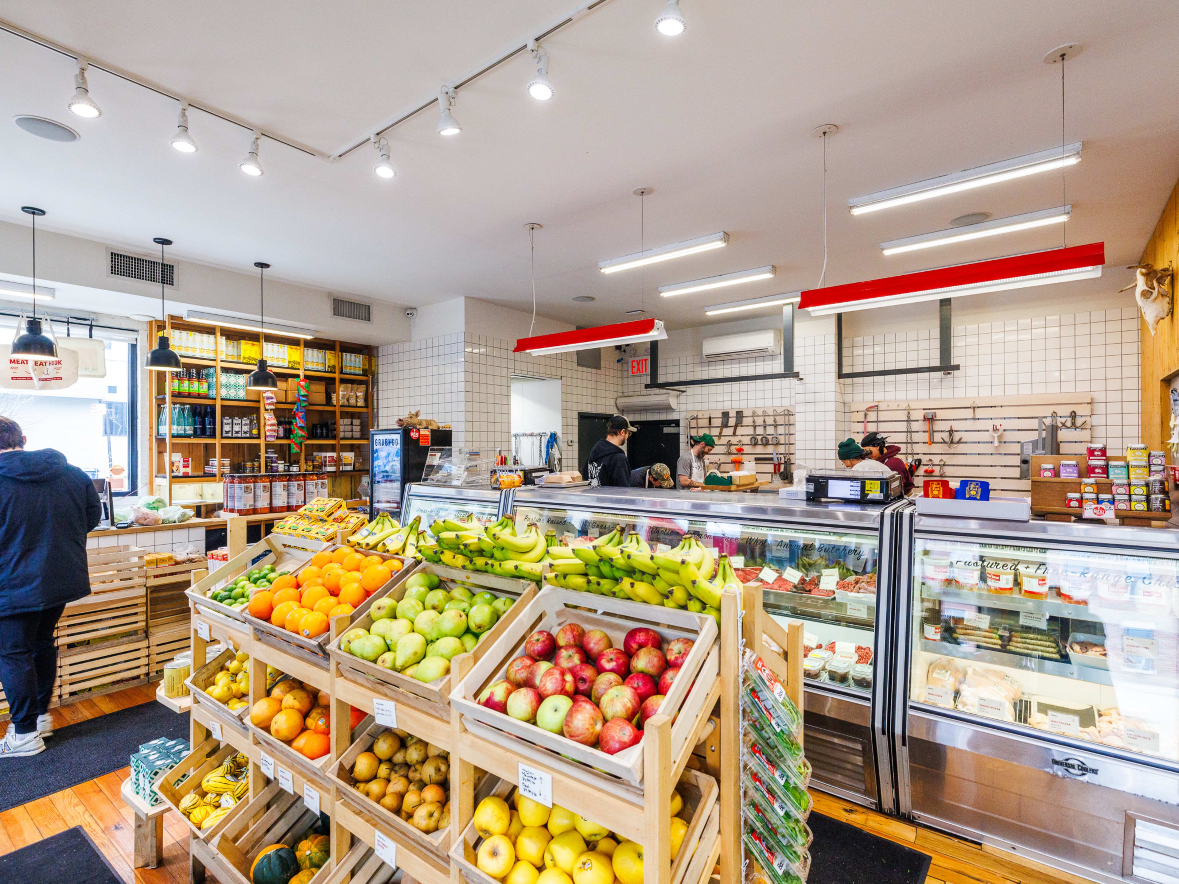 The Meat Hook interiors with bright lighting, fruits on display in wooden crates, and meats on display in a refrigerated glass counter