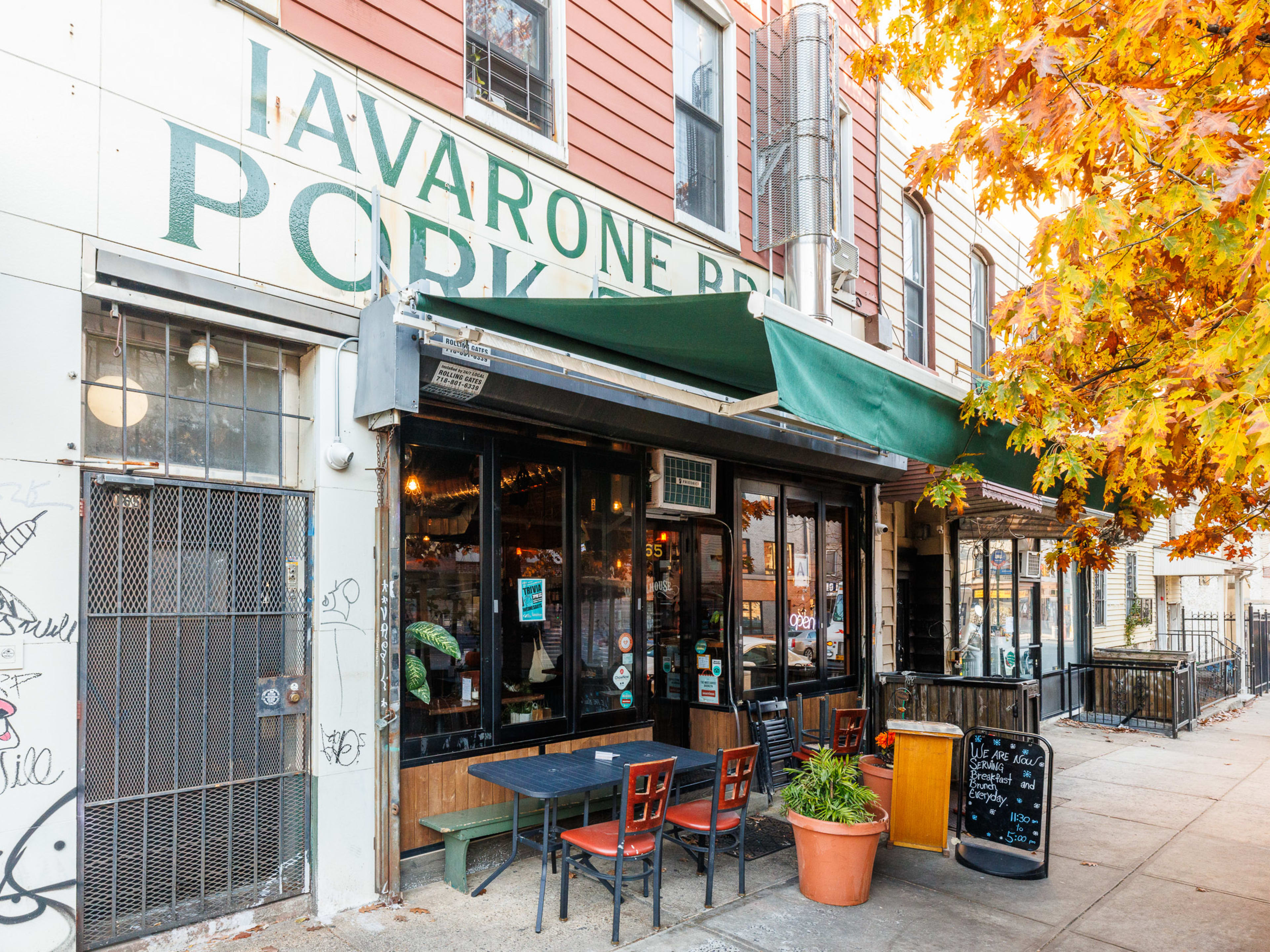 The Wheelhouse exterior with outdoor sidewalk seating, a green awning, and fall leaves on the tree out front