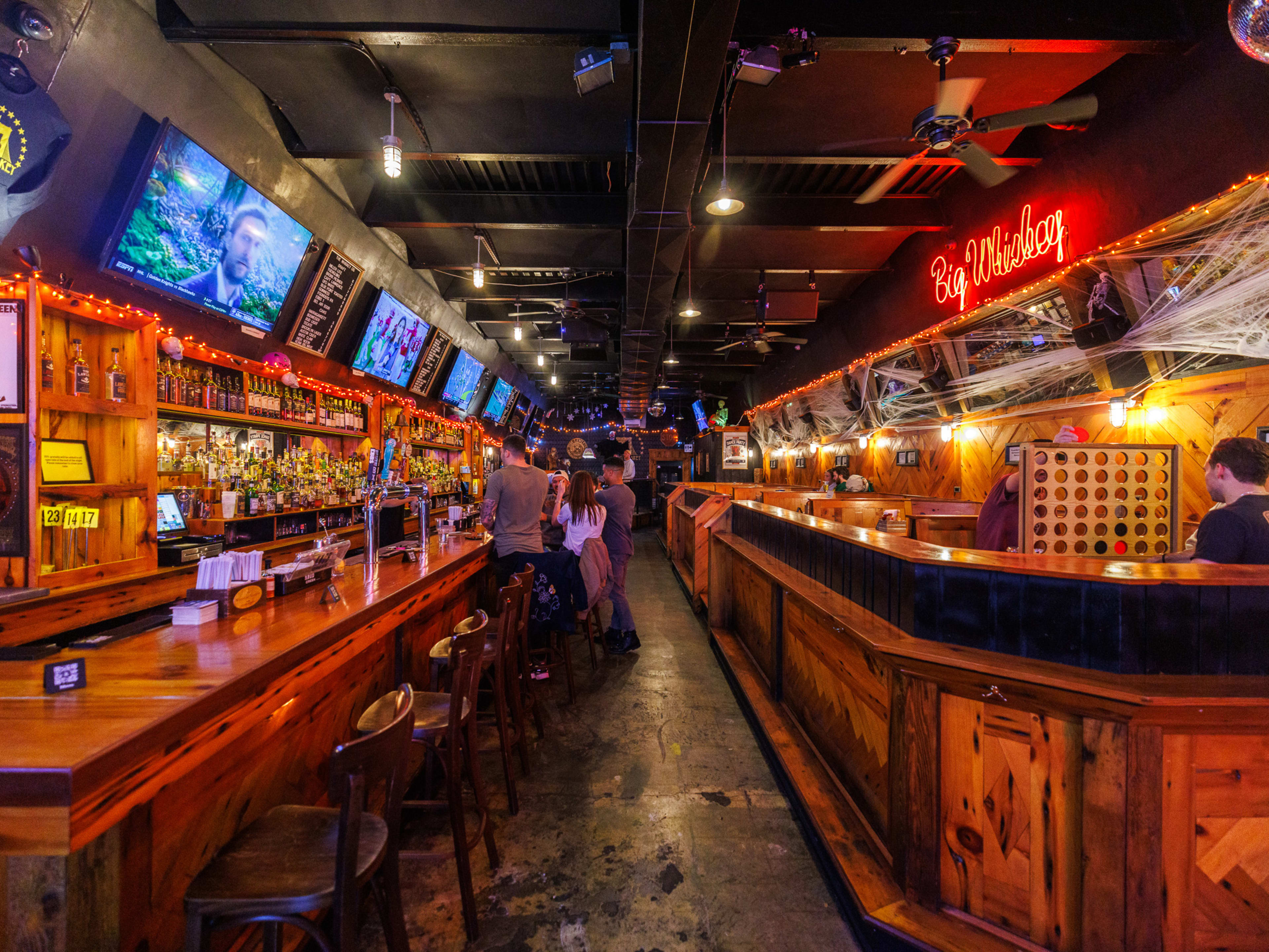 Interior at The Whiskey on Grand with bar seating, a neon sign, and tvs