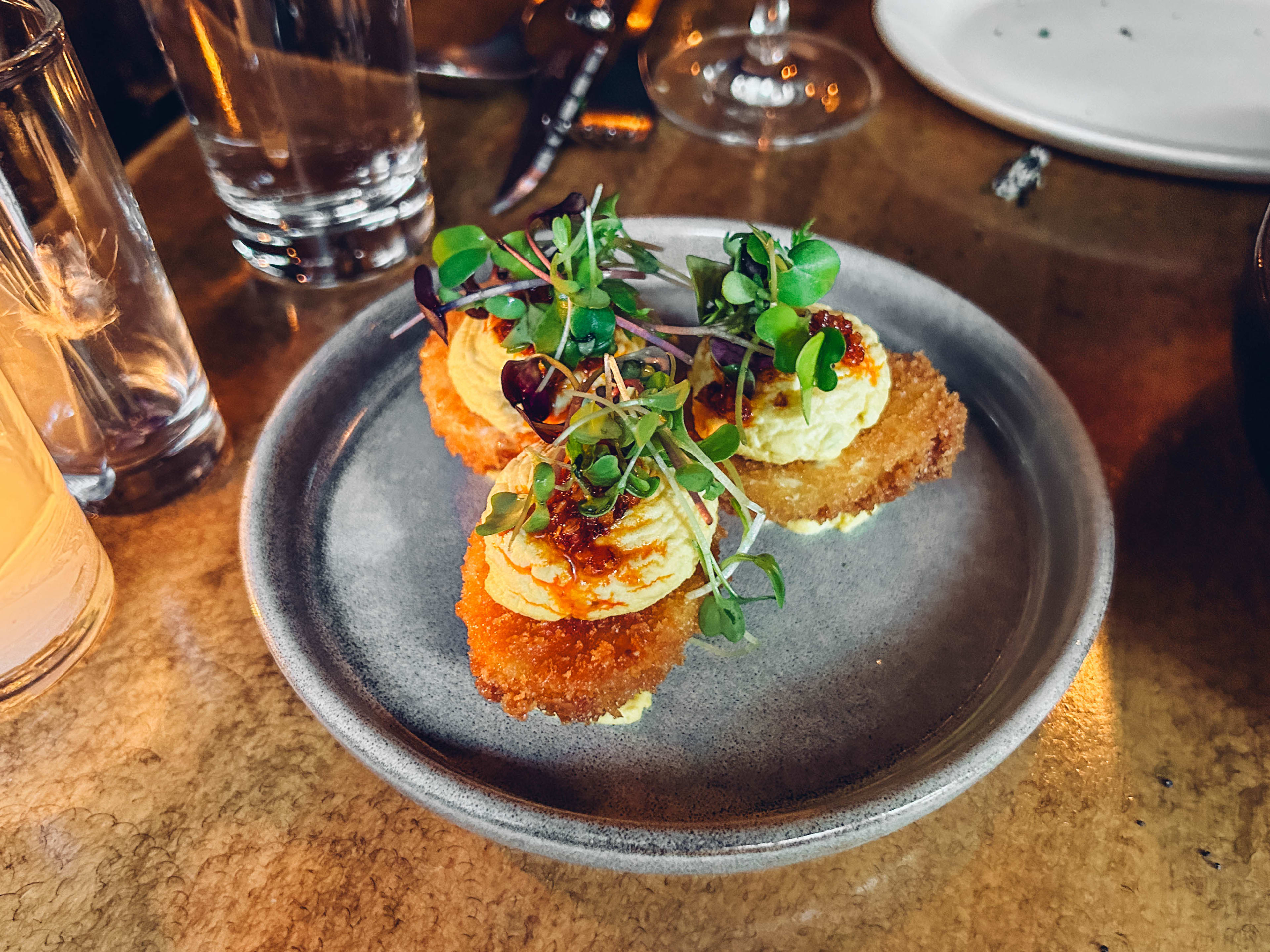 three deep-fried deviled eggs topped with chili chip and micro greens