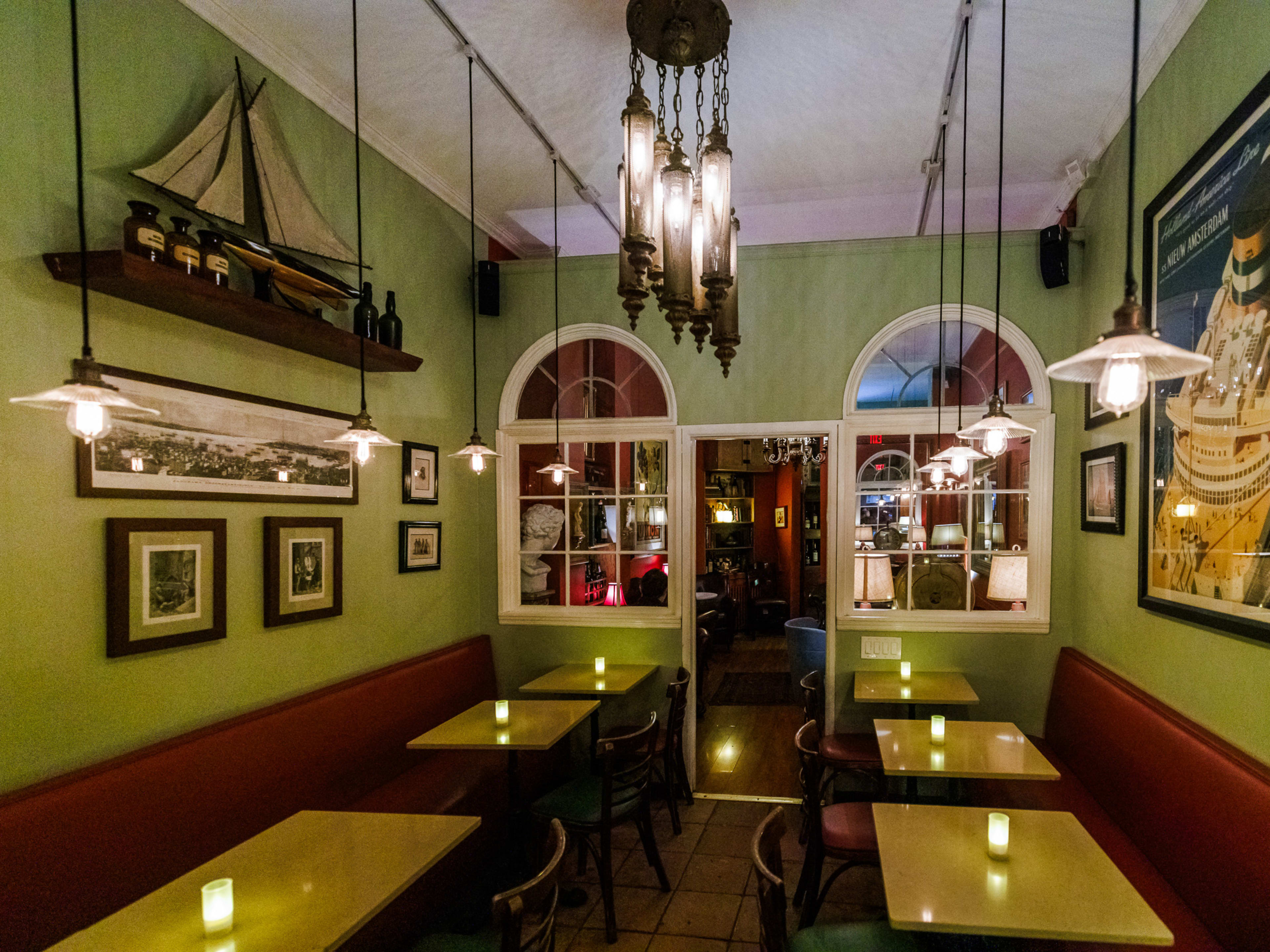 Turks & Frogs interiors with green walls, a boat on display on the wall, and candles on tables with red booth seating