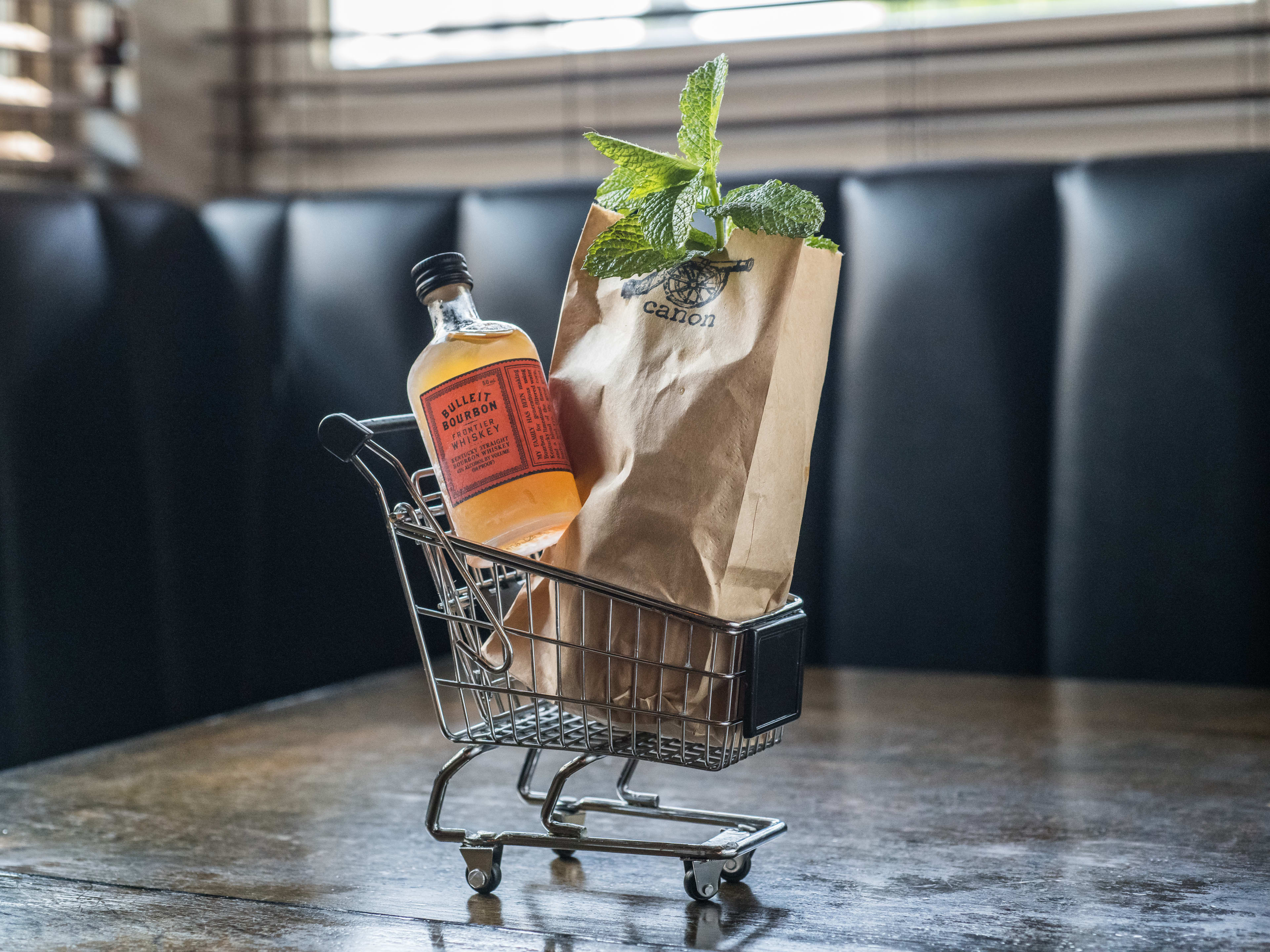 Cocktail comprising a miniature shopping cart with a paper bag full of mint, plus a small bottle containing a ready-to-drink cocktail.