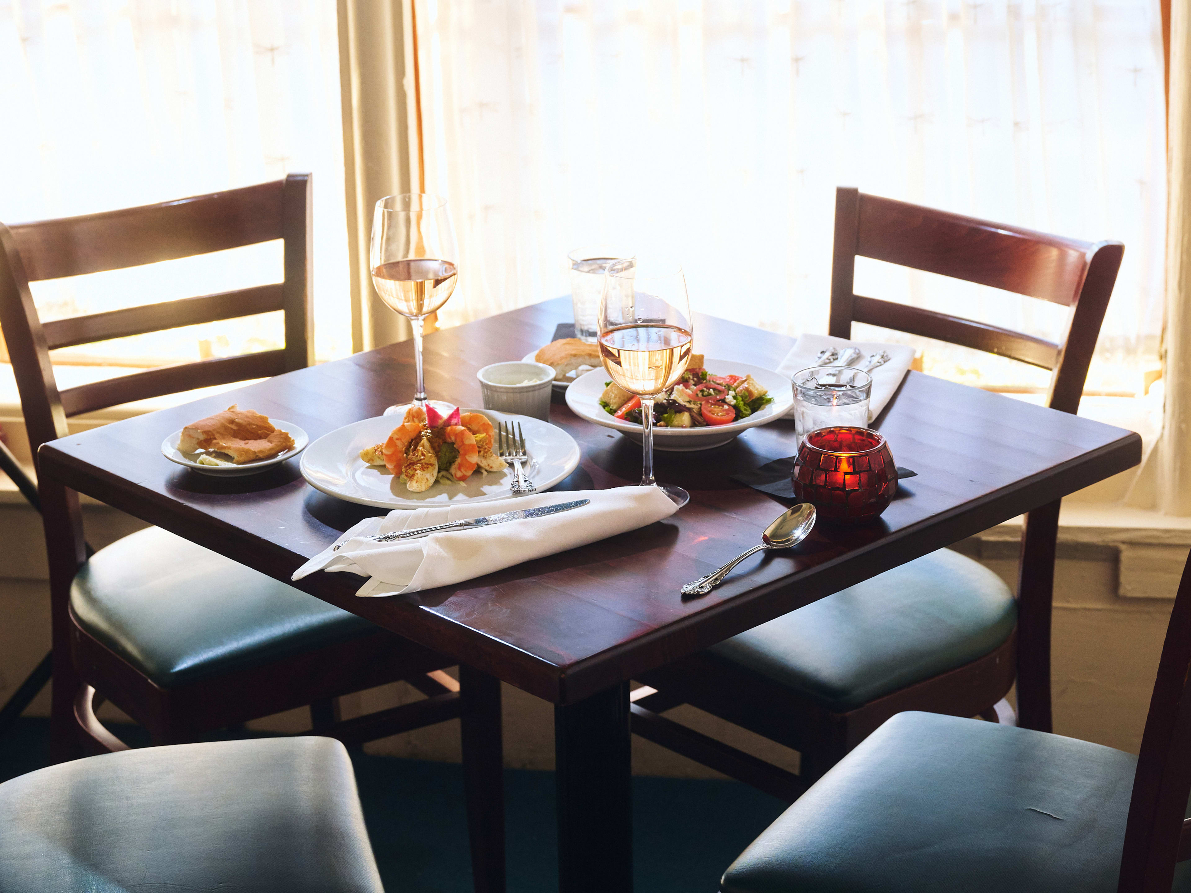 Brigtsen’s Restaurant table next to the window with wine and two entrees