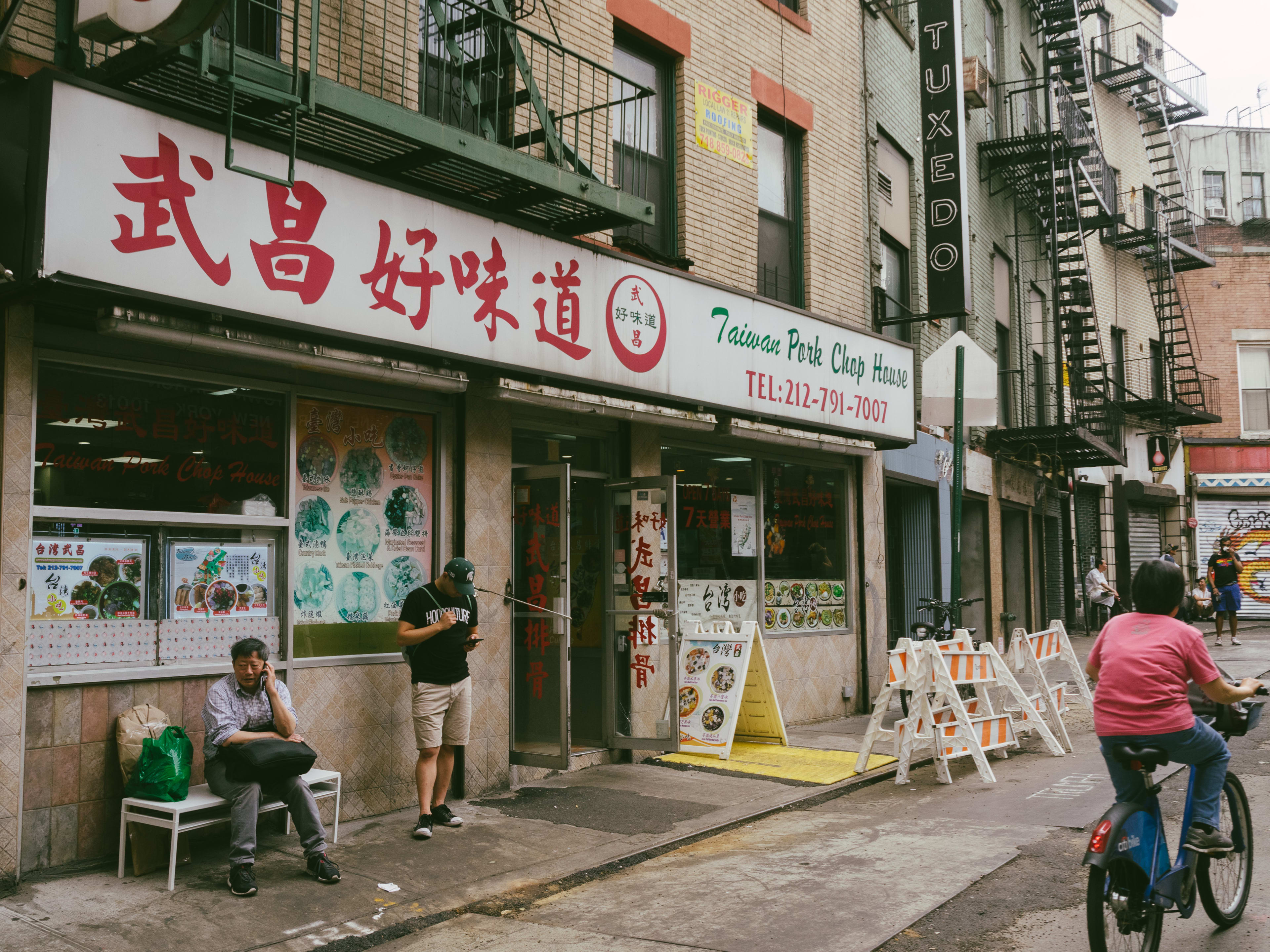 Taiwan Pork Chop House exterior with people riding by on bikes in the street