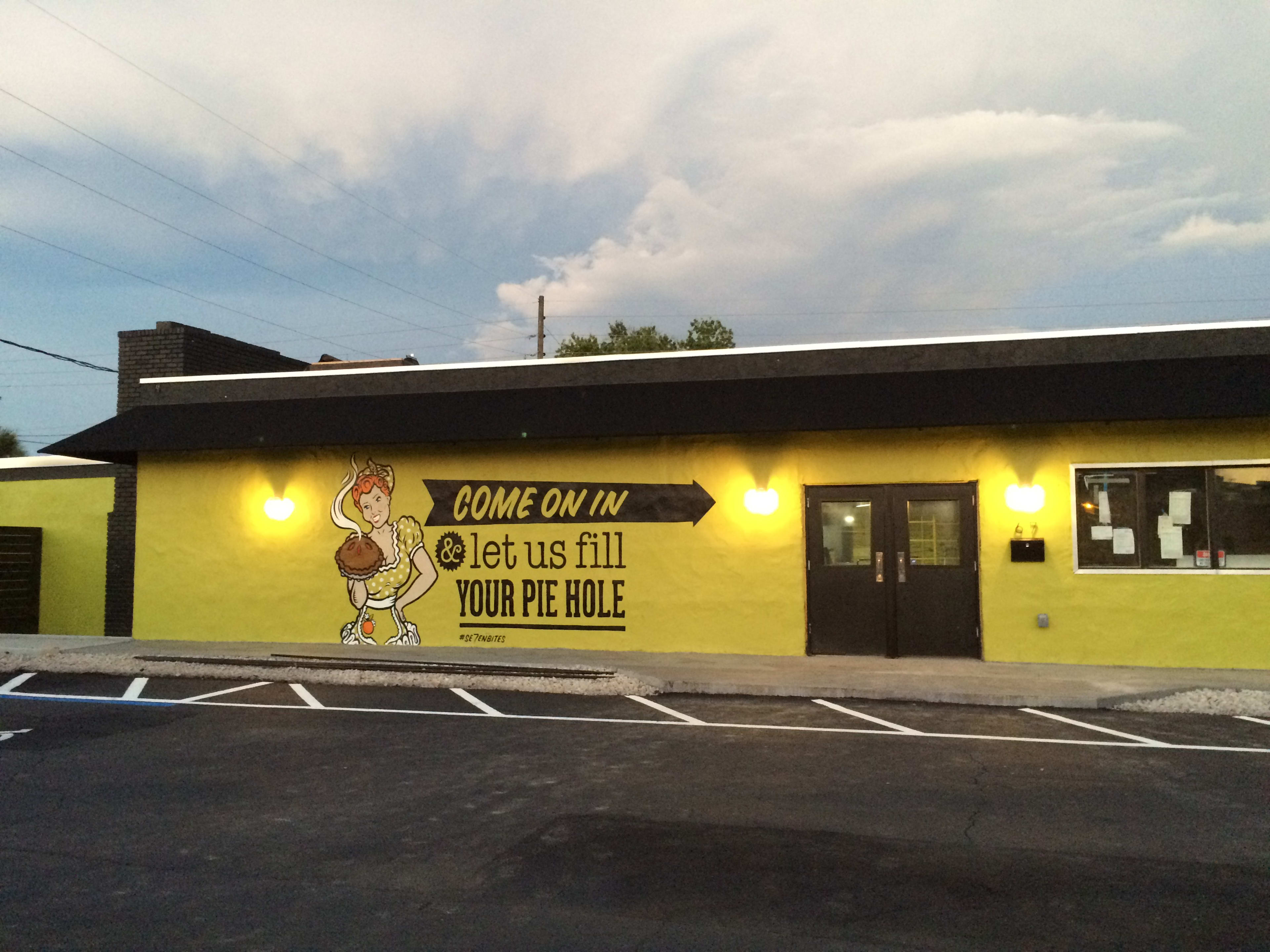 Se7en Bites exterior with yellow walls and a mural painted on the front of the restaurant