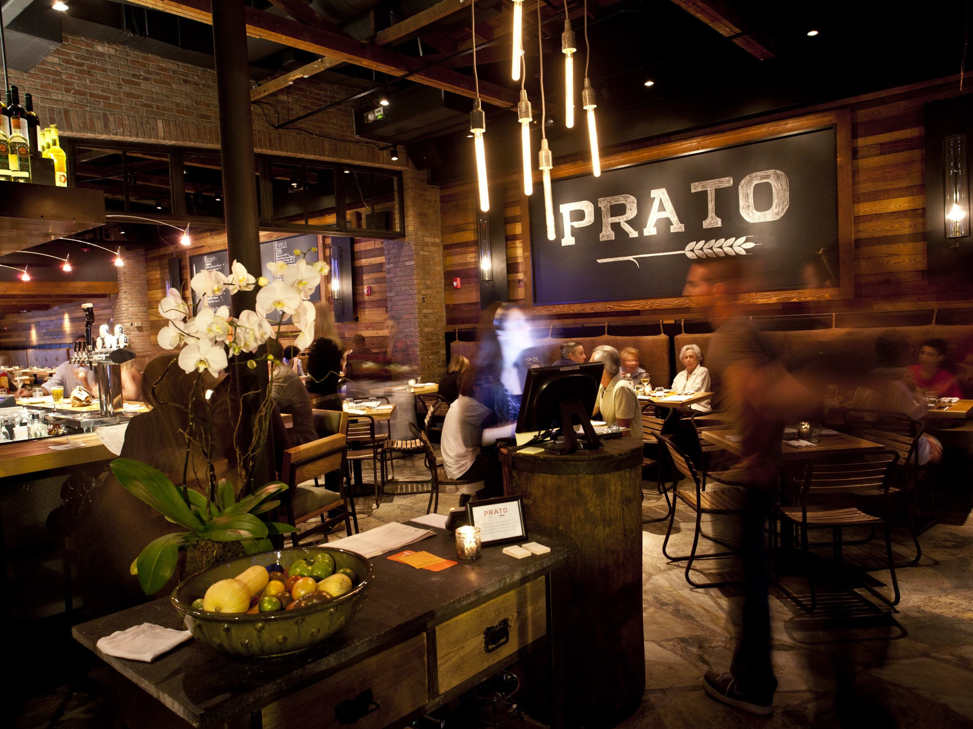 Prato interiors with wood paneled walls, dim lighting, and blurred people moving throughout the space