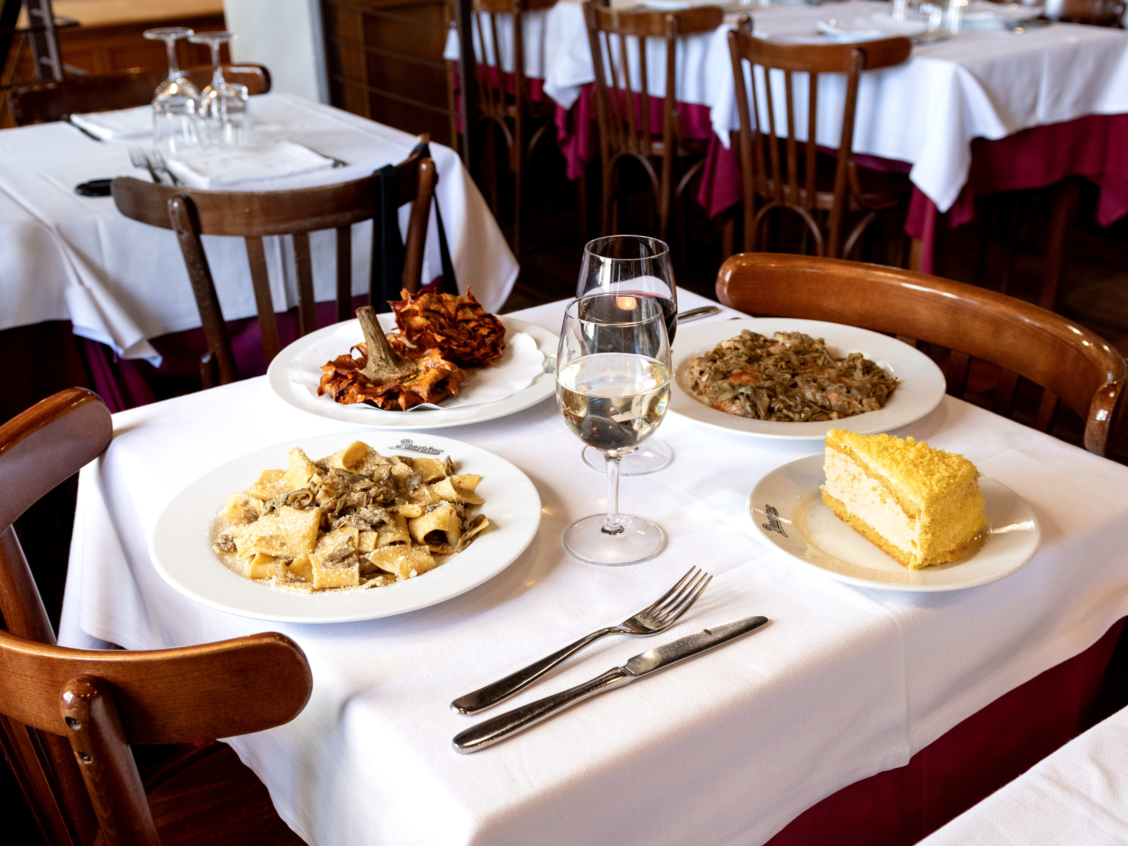 Spread of dishes and white wine on white tablecloth at Pecorino