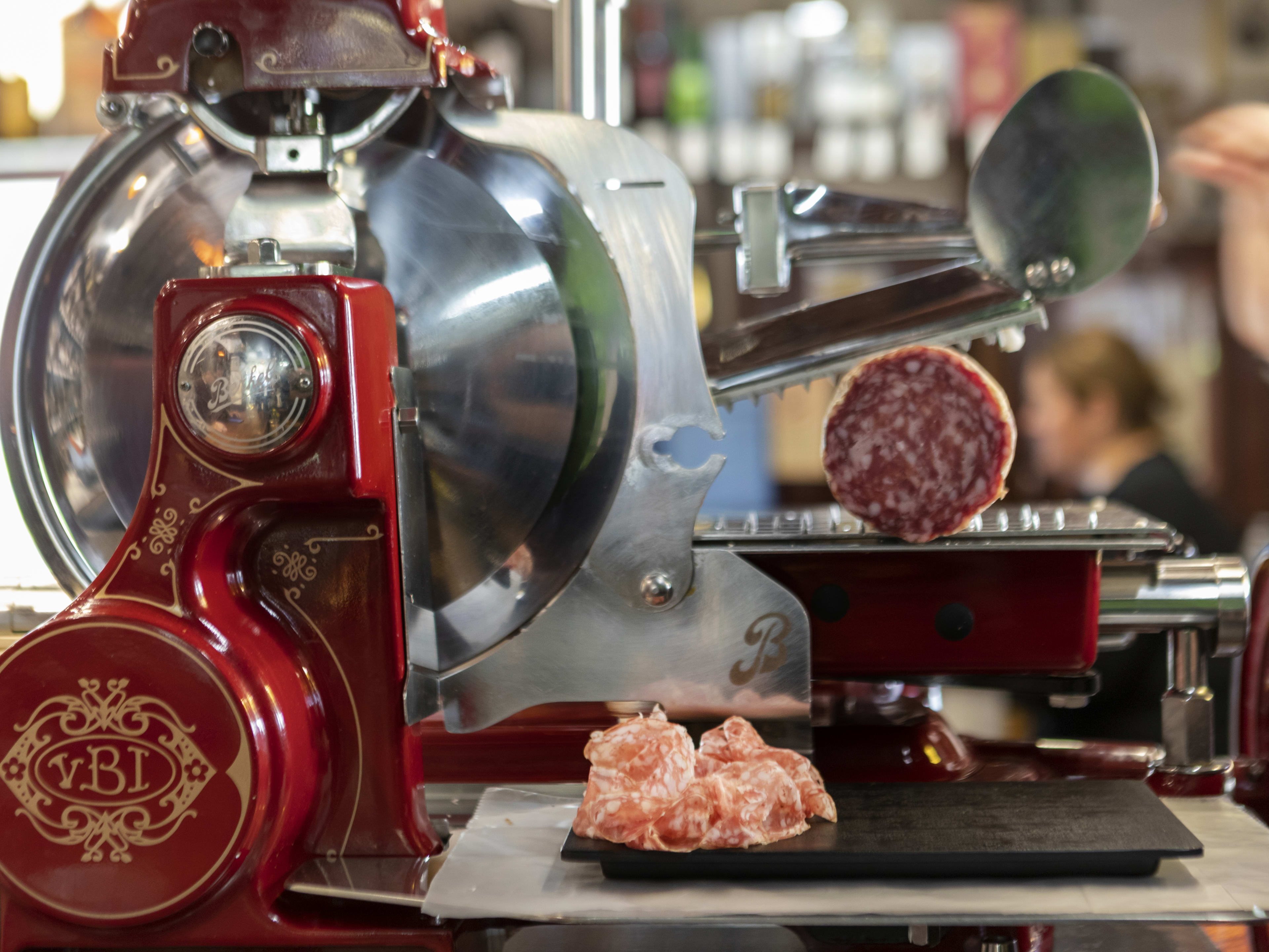 Red-accented meat grinder churning out fresh salami at Enoteca Picone