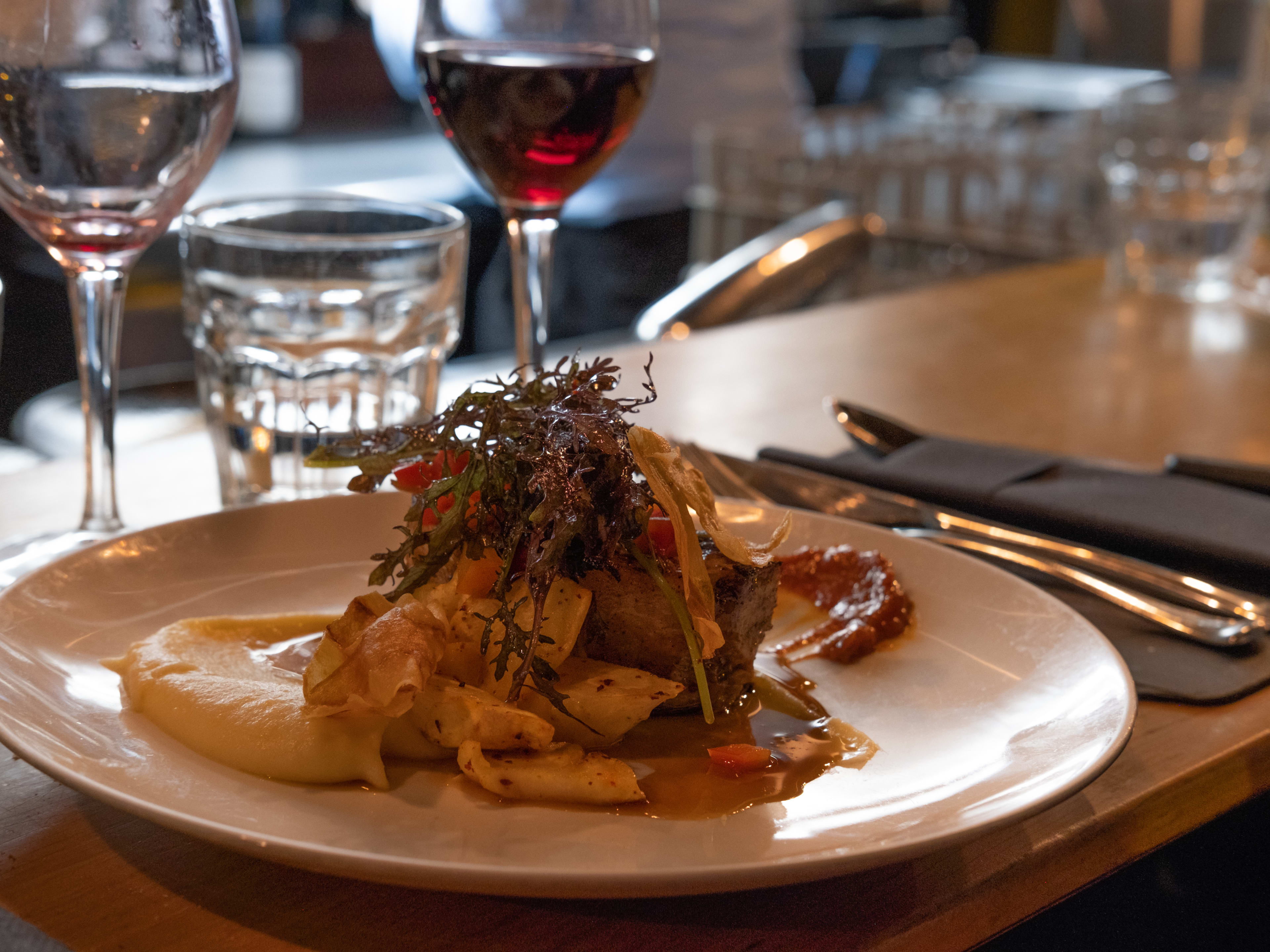 Dish on the bar at Pierre Sang with a glass of red wine in the background