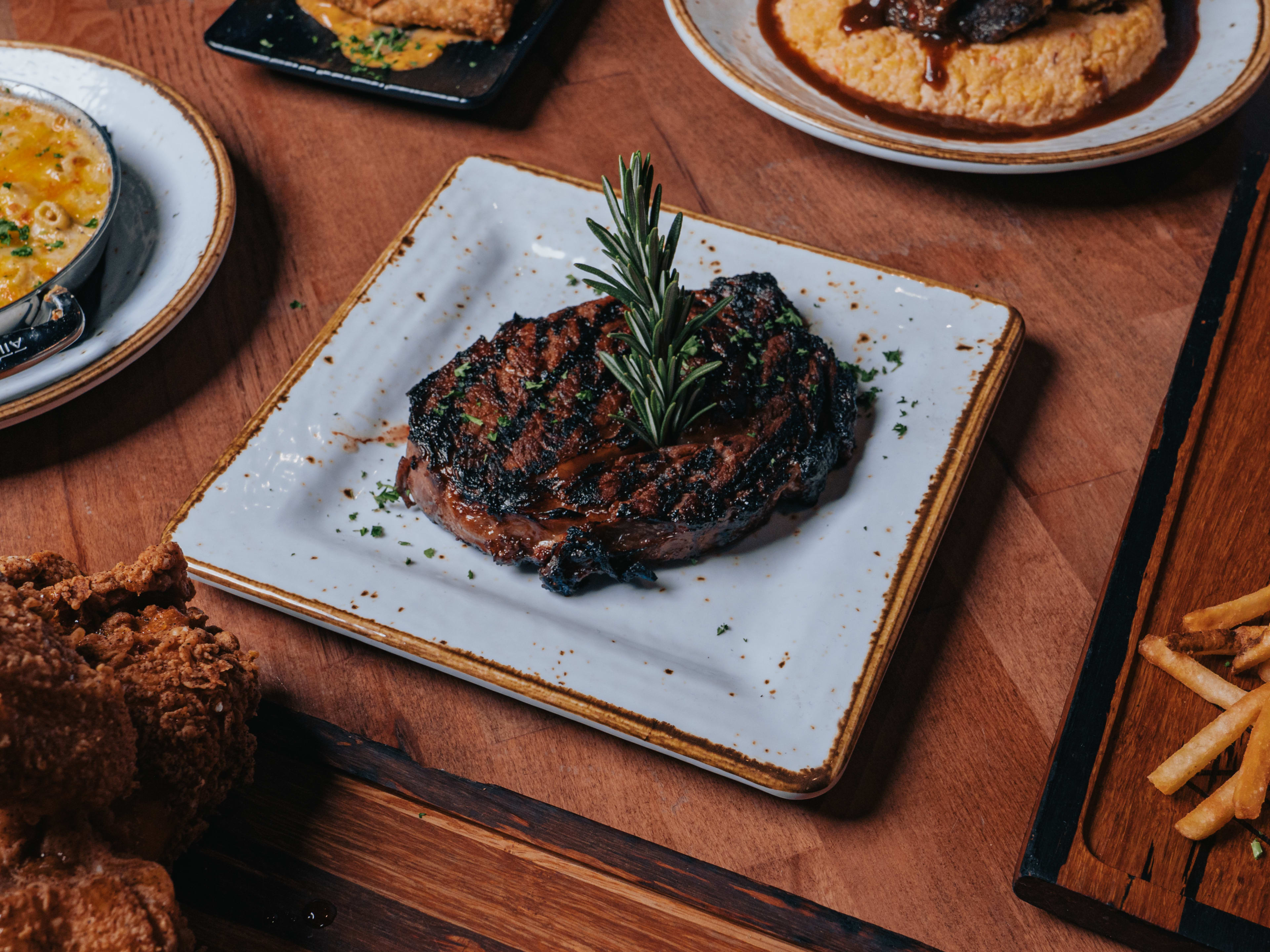 Rockhouse Southern Kitchen plate of steak with other dishes surrounding it on a wooden table