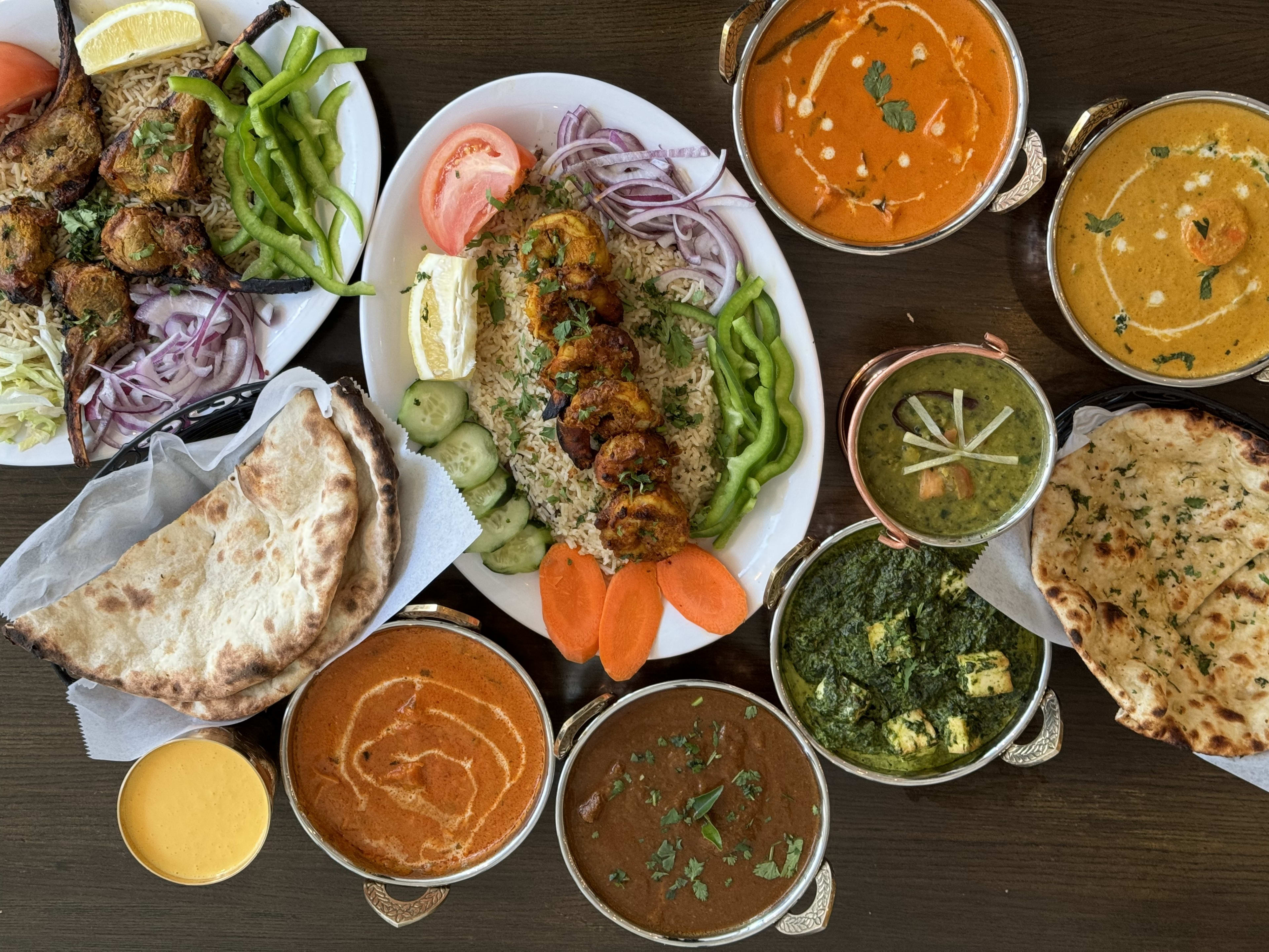 Large spread of curries, naan, and a platter of meats and rice