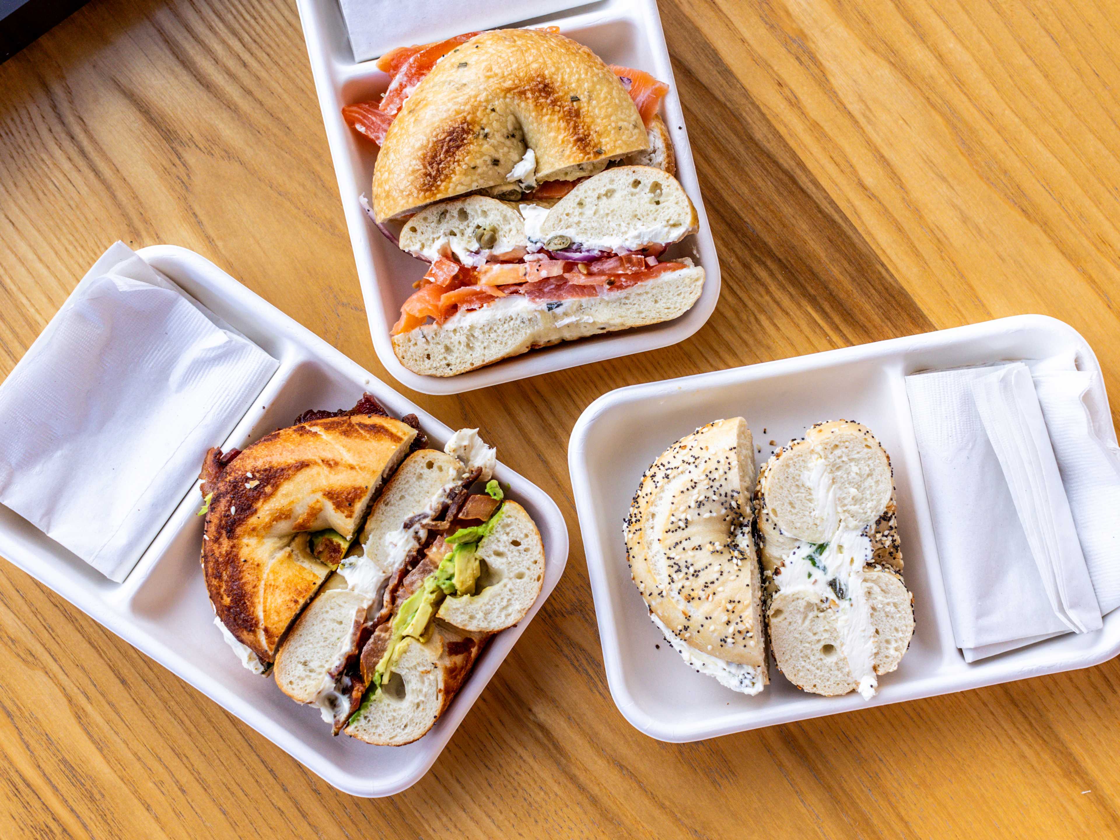 A spread of bagels in takeaway containers from Rosen's Bagels.