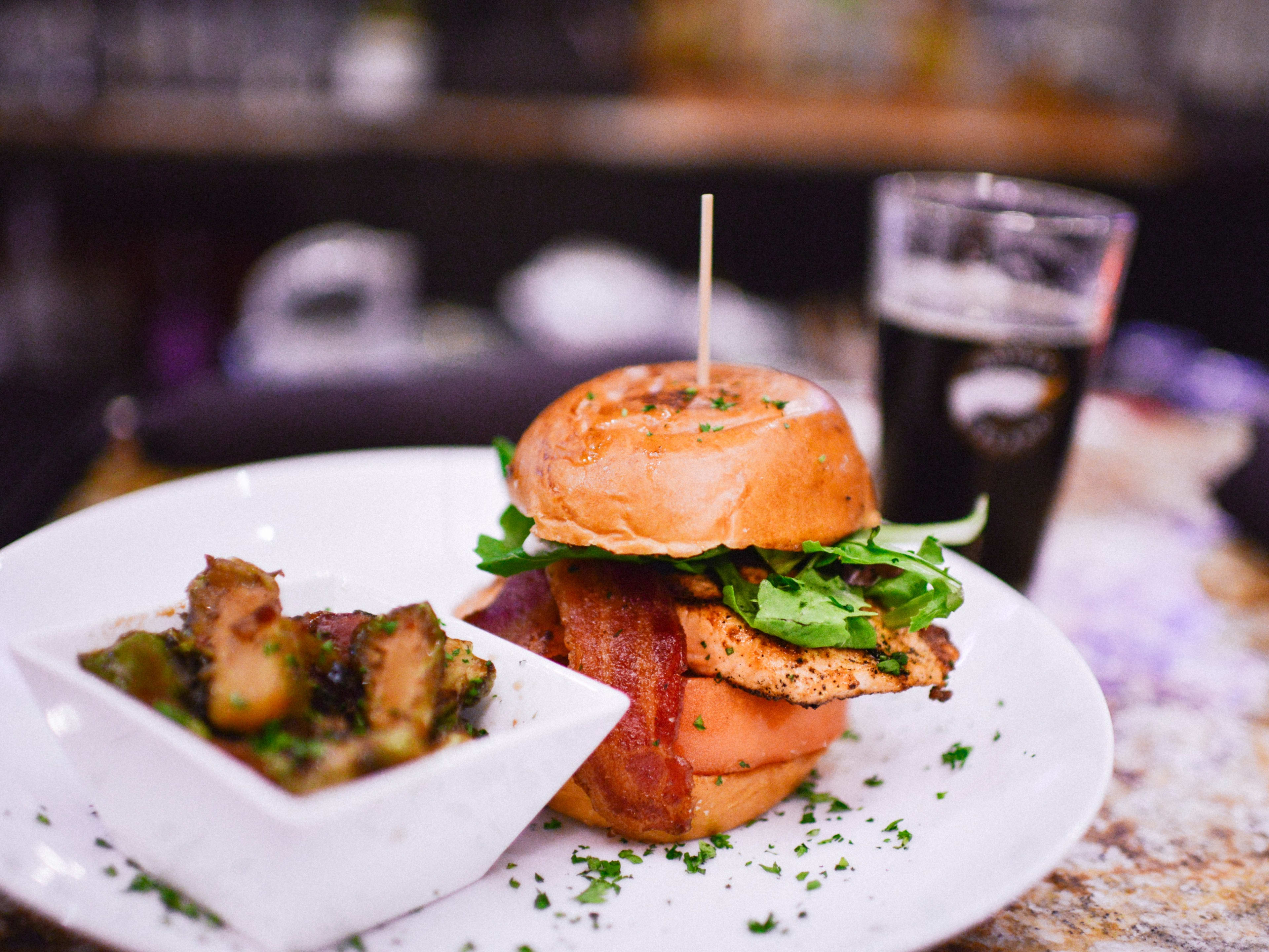 RusTeak chicken sandwich with bacon lettuce and tomato on a plate with fries