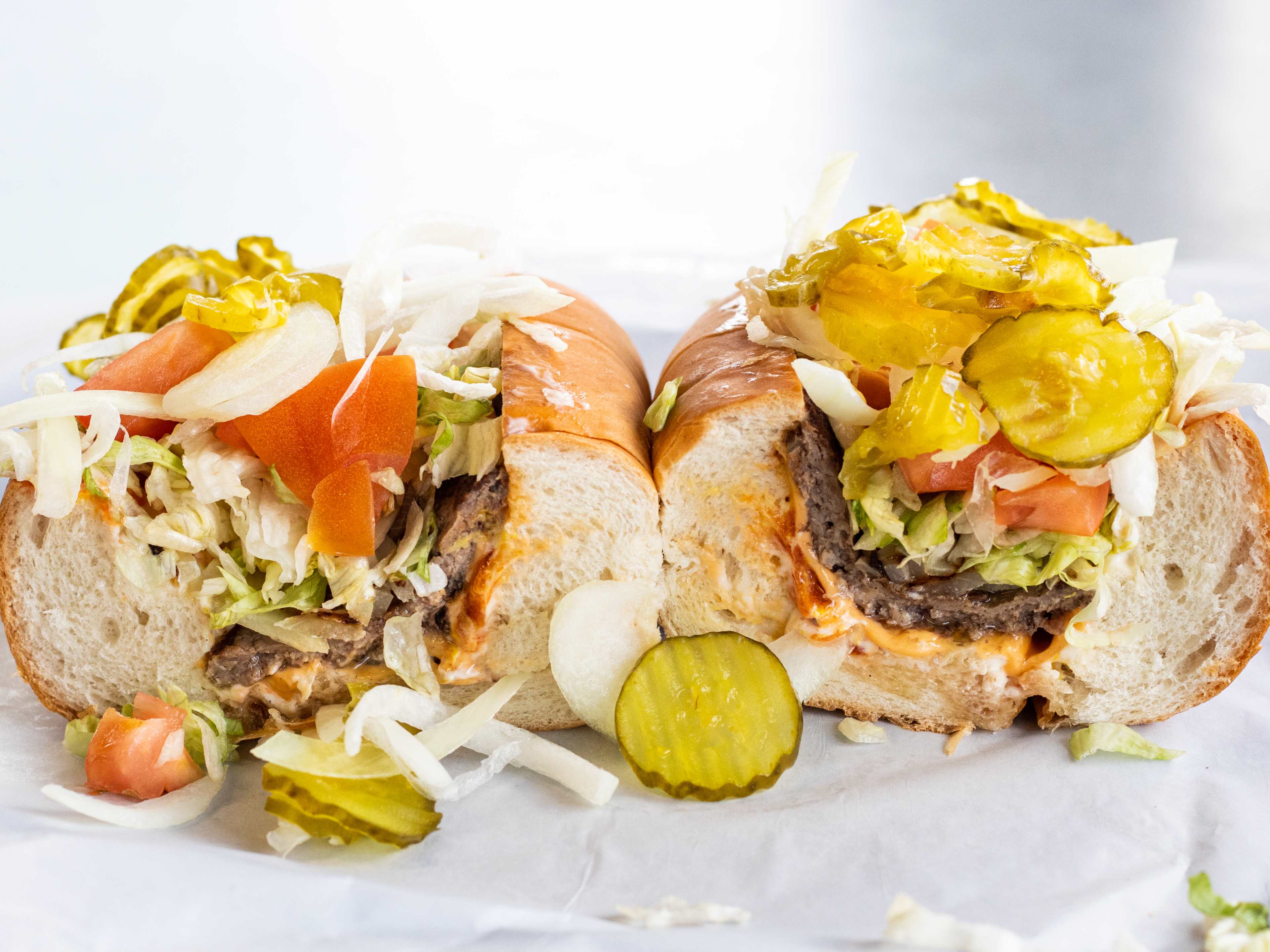 cheeseburger sub with meat, cheese, lettuce, tomatoes, and pickles