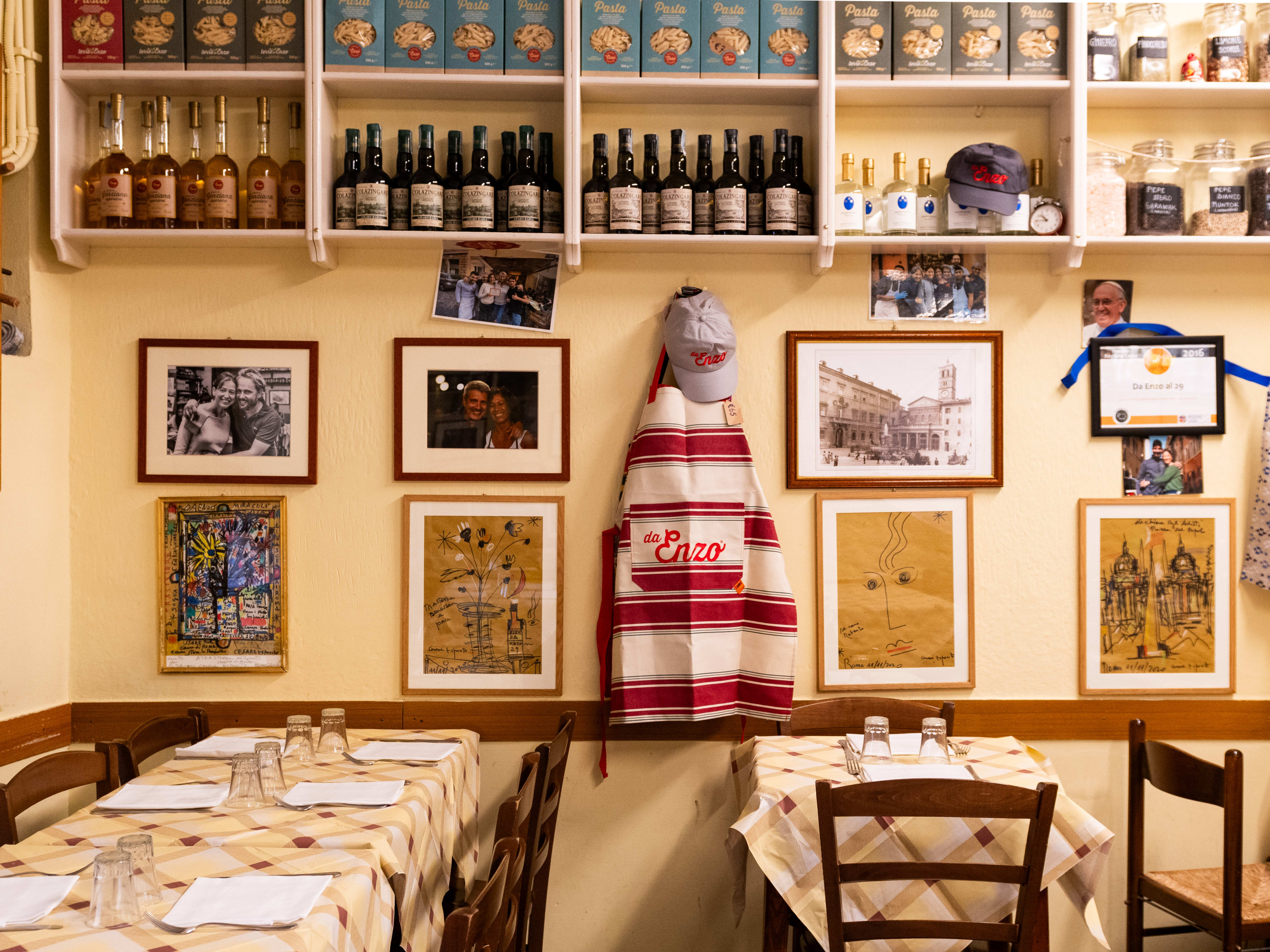 Interior dining room space with wall of bottles and ingredients on shelves at Trattoria da Enzo al 29