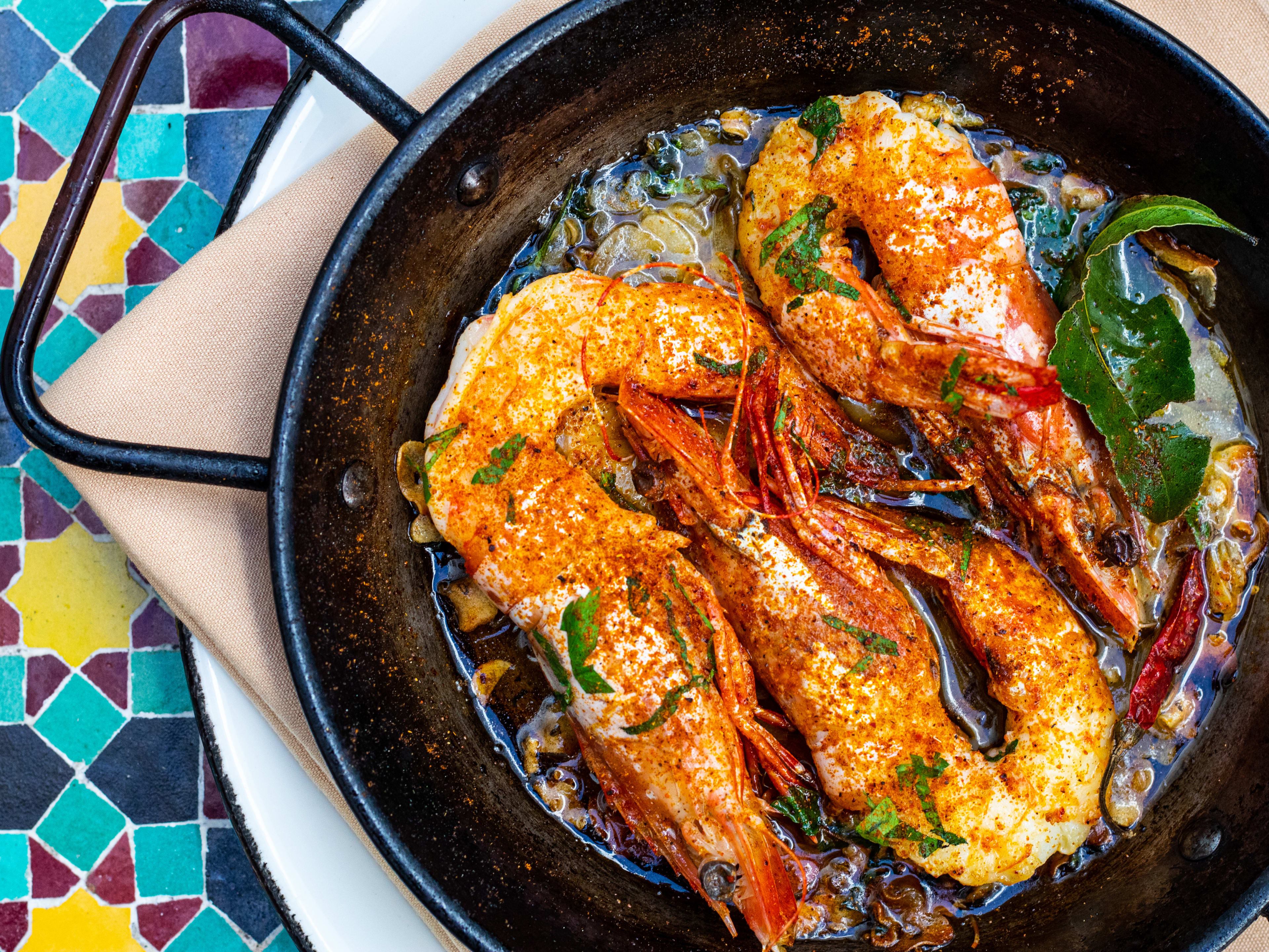 head and tail on shrimp in oil in a skillet on tiled table