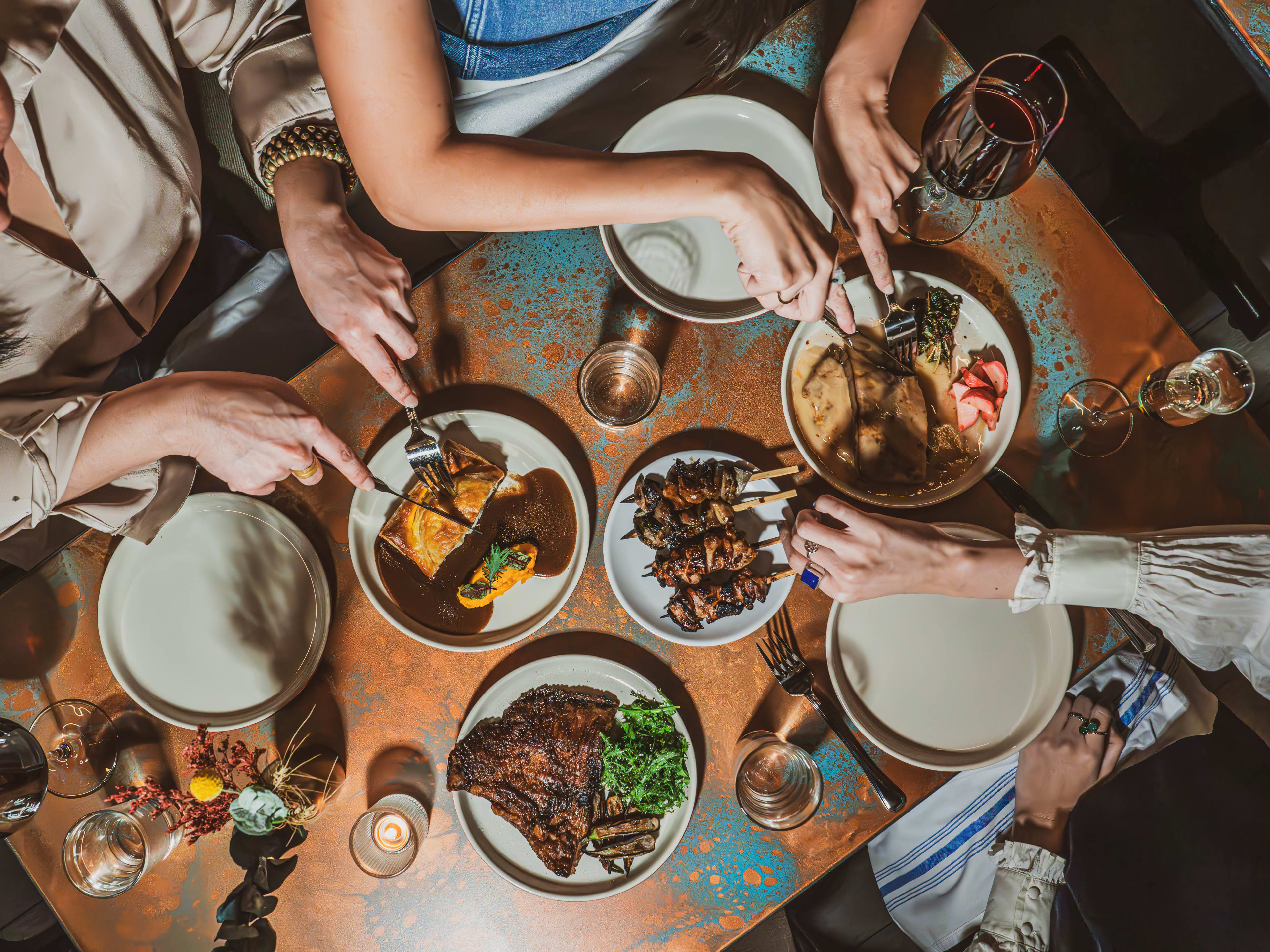 Several dishes on a table with people's hands eating at Ramro.