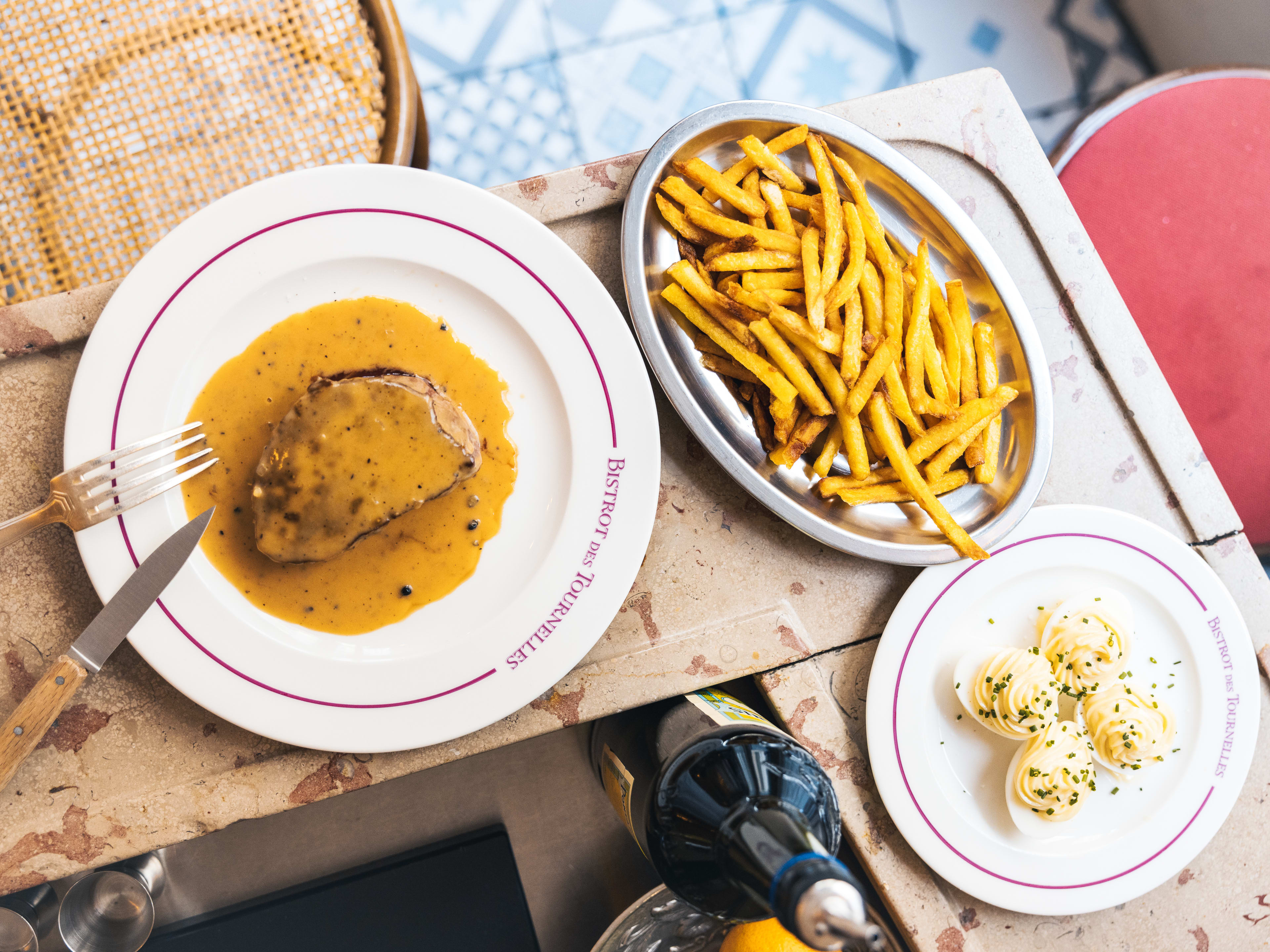 Spread of classic French dishes on small outdoor bar space at Bistrot des Tournelles