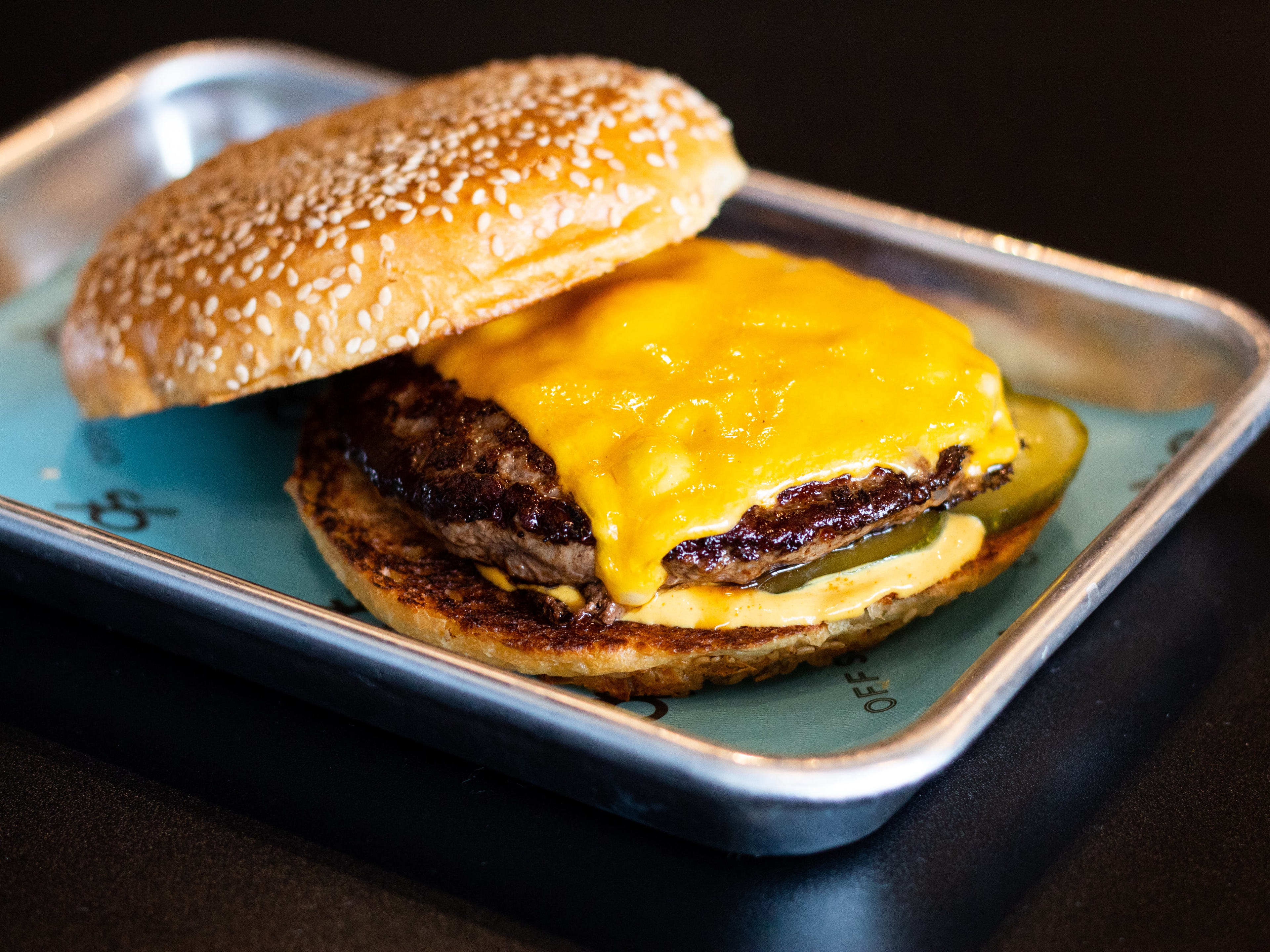 A cheeseburger on a silver tray.