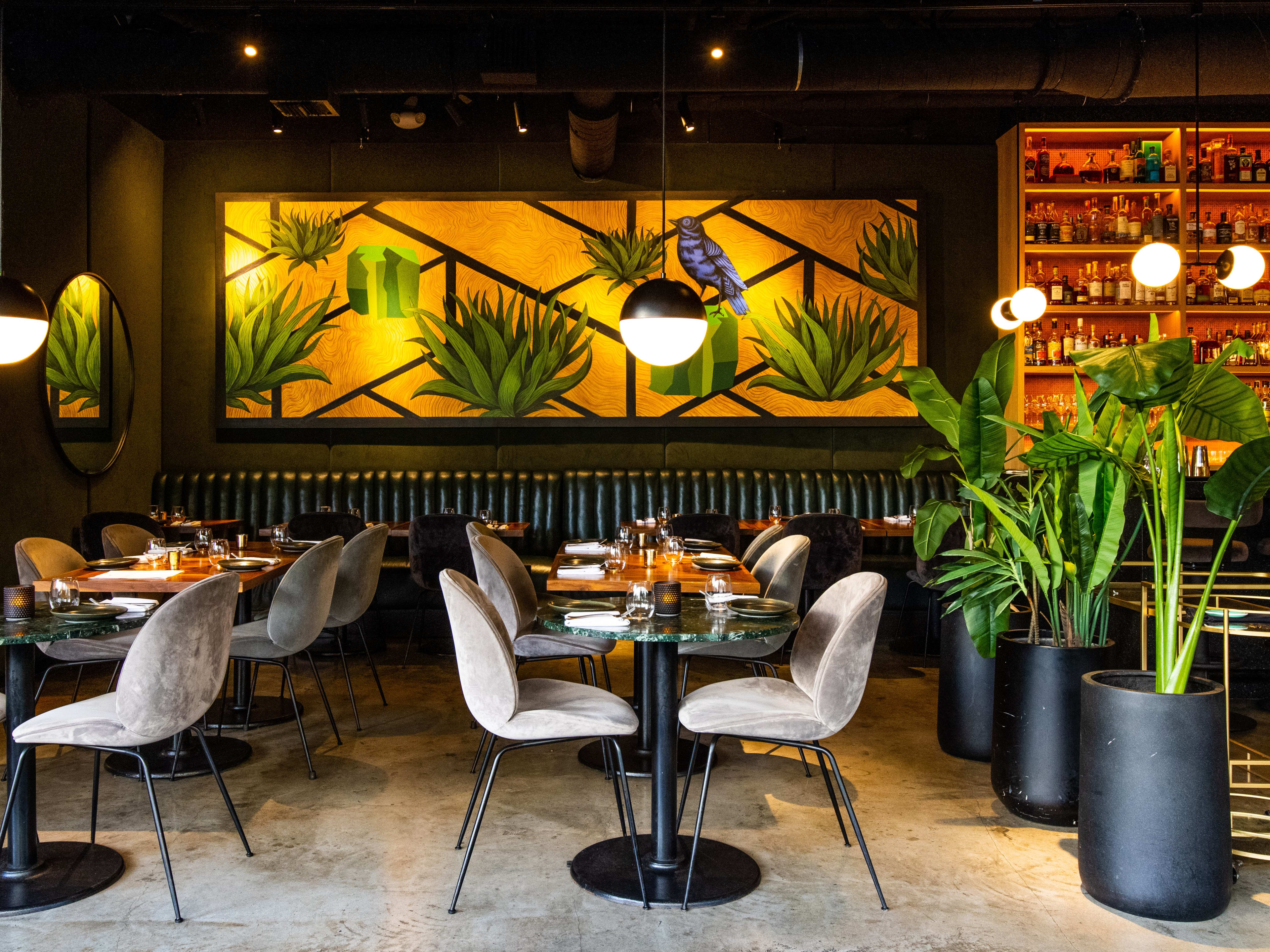 A dining room with plants and a mural of a bird.