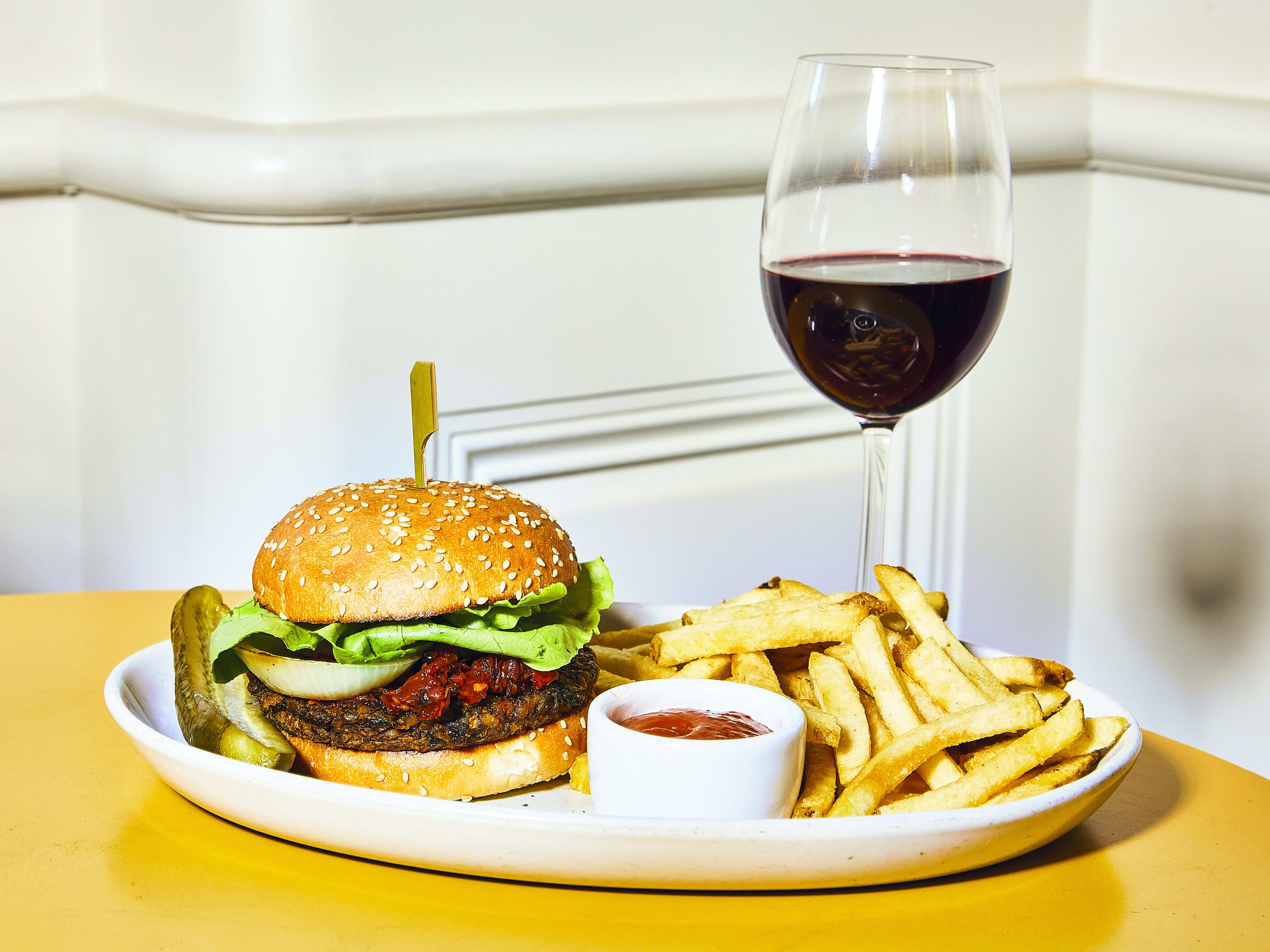 burger with fries and ketchup next to a glass of red wine