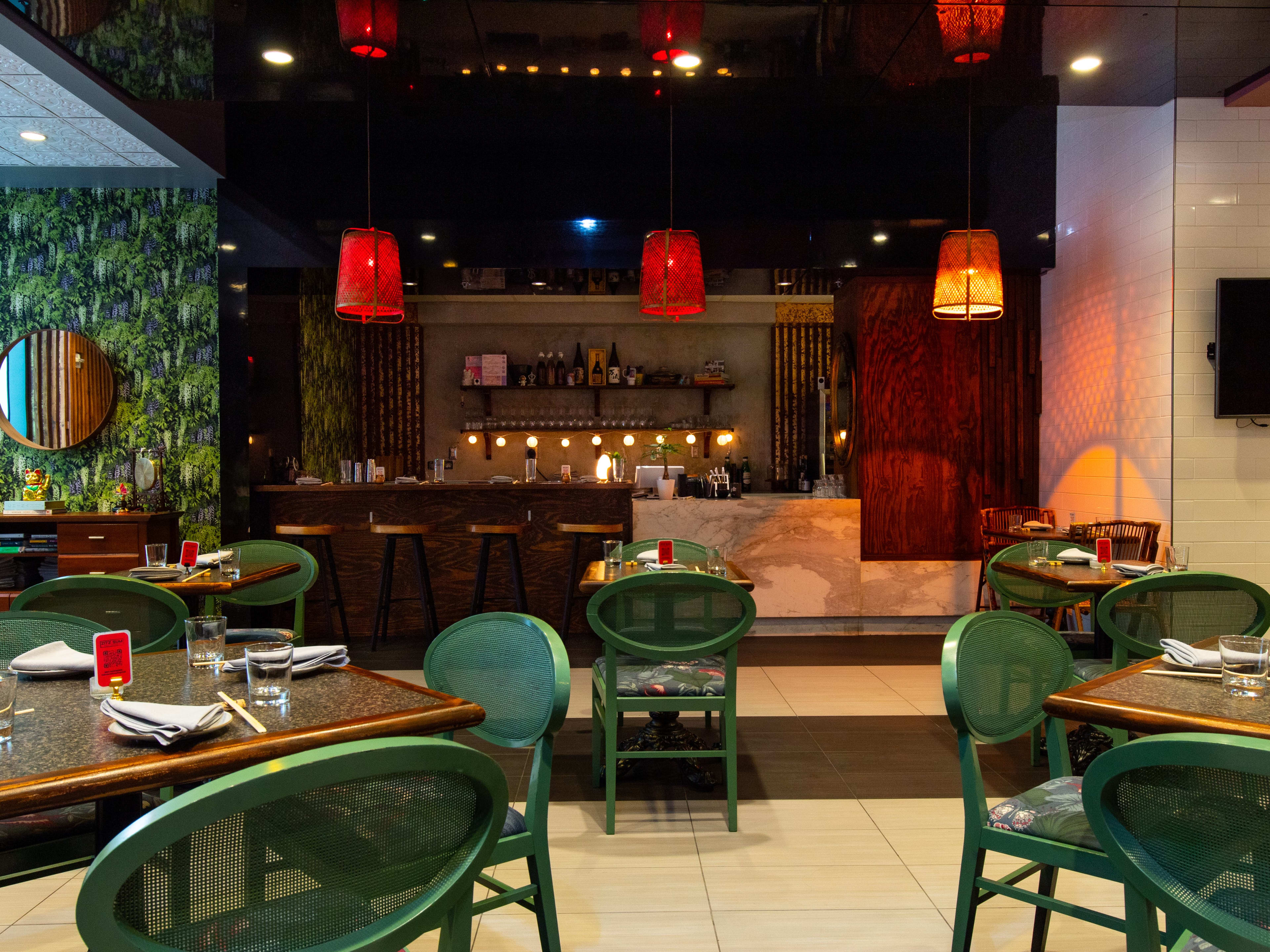 Tables with green chairs in a dark dining room.