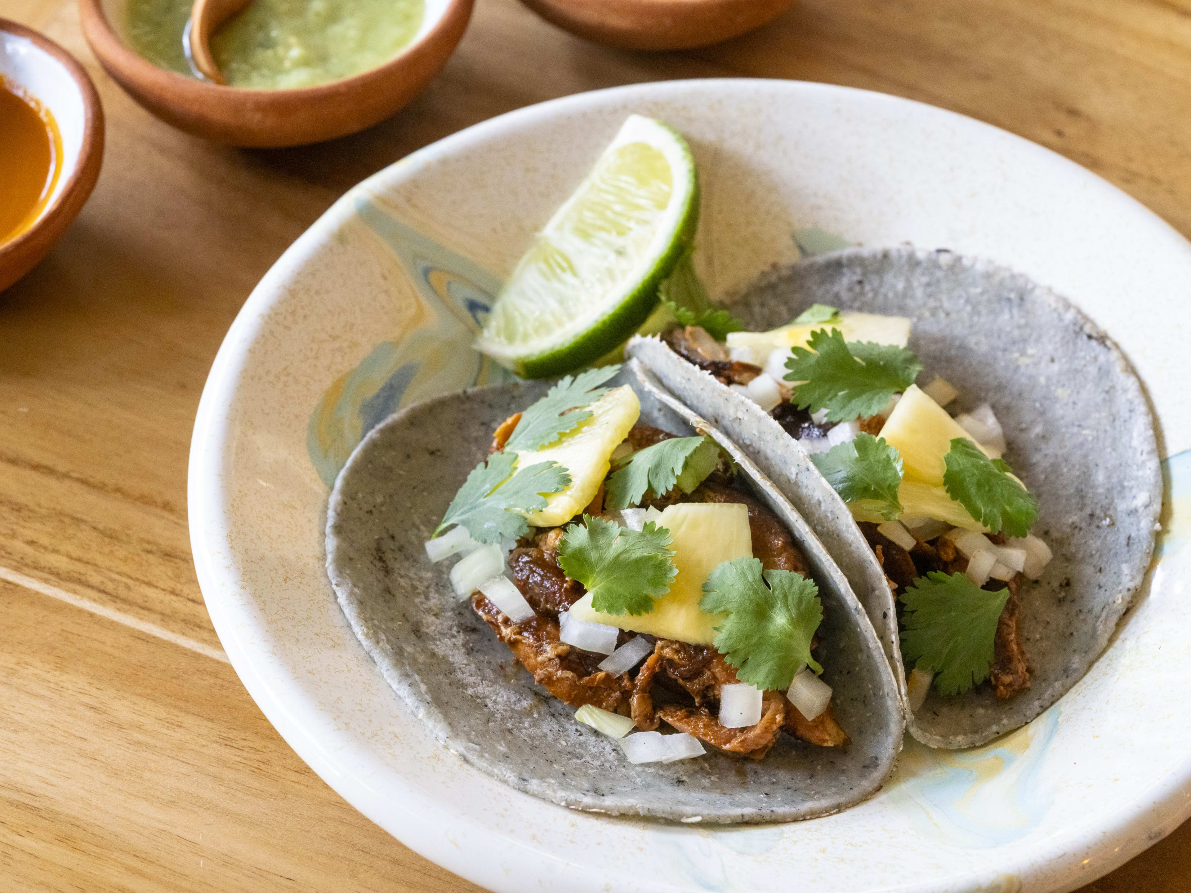 blue corn tortilla with meat garnish and lime wedge