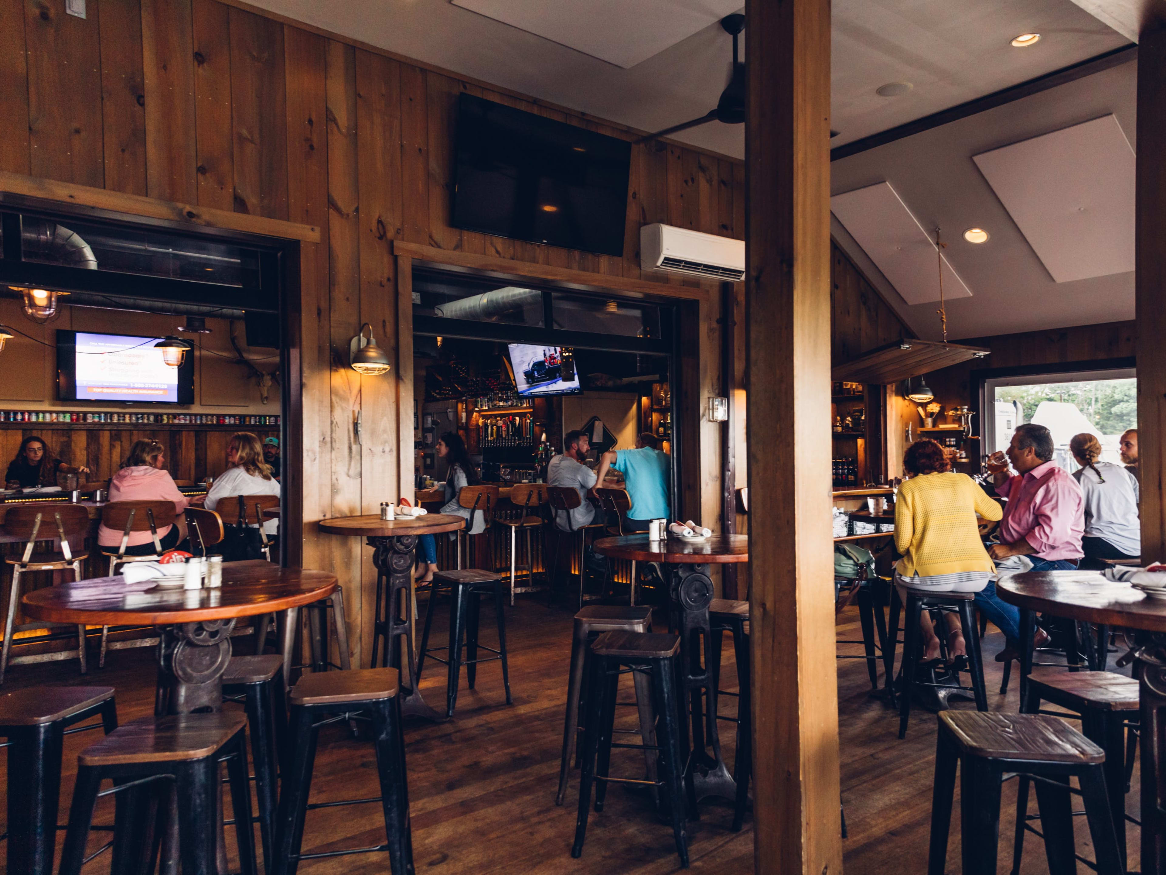 Old Causeway interiors with wood paneled walls and people seated at high top wooden tables