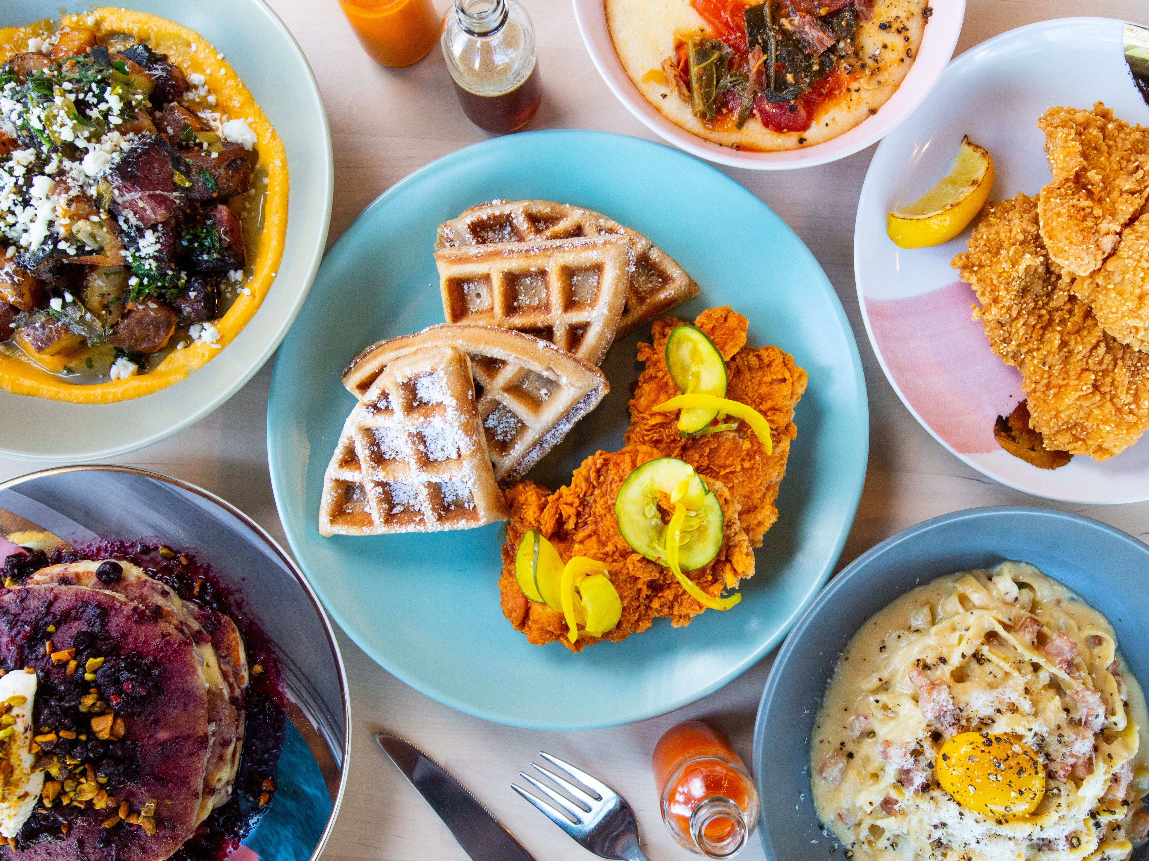 spread of brunch dishes such as chicken and waffles, pancakes, carbonara, fried chicken