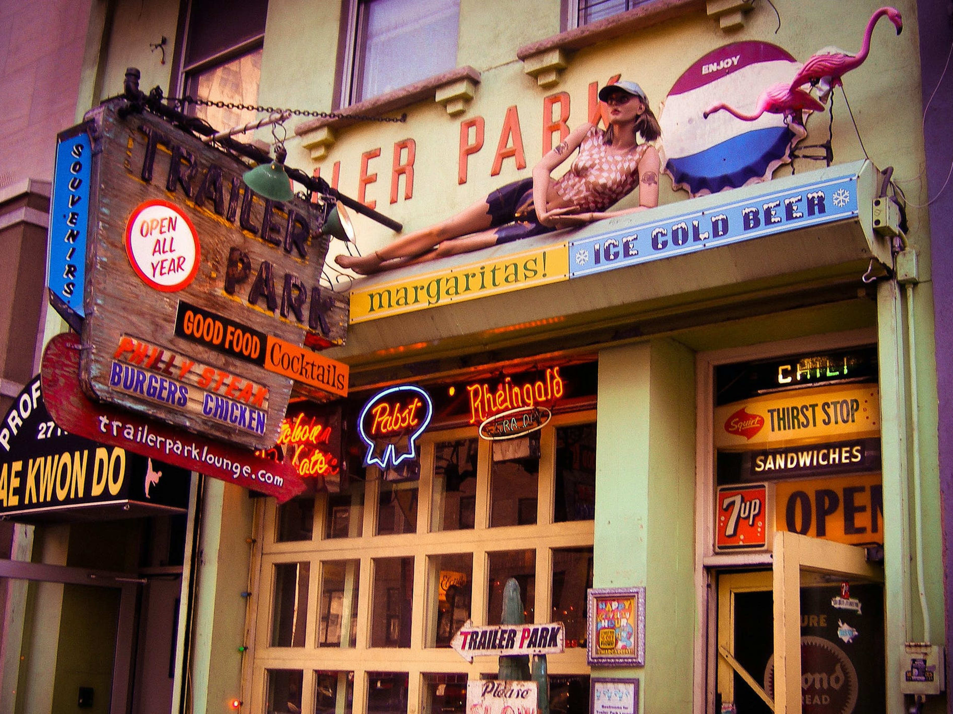 The exterior of a bar covered in beer signs and vintage decor.