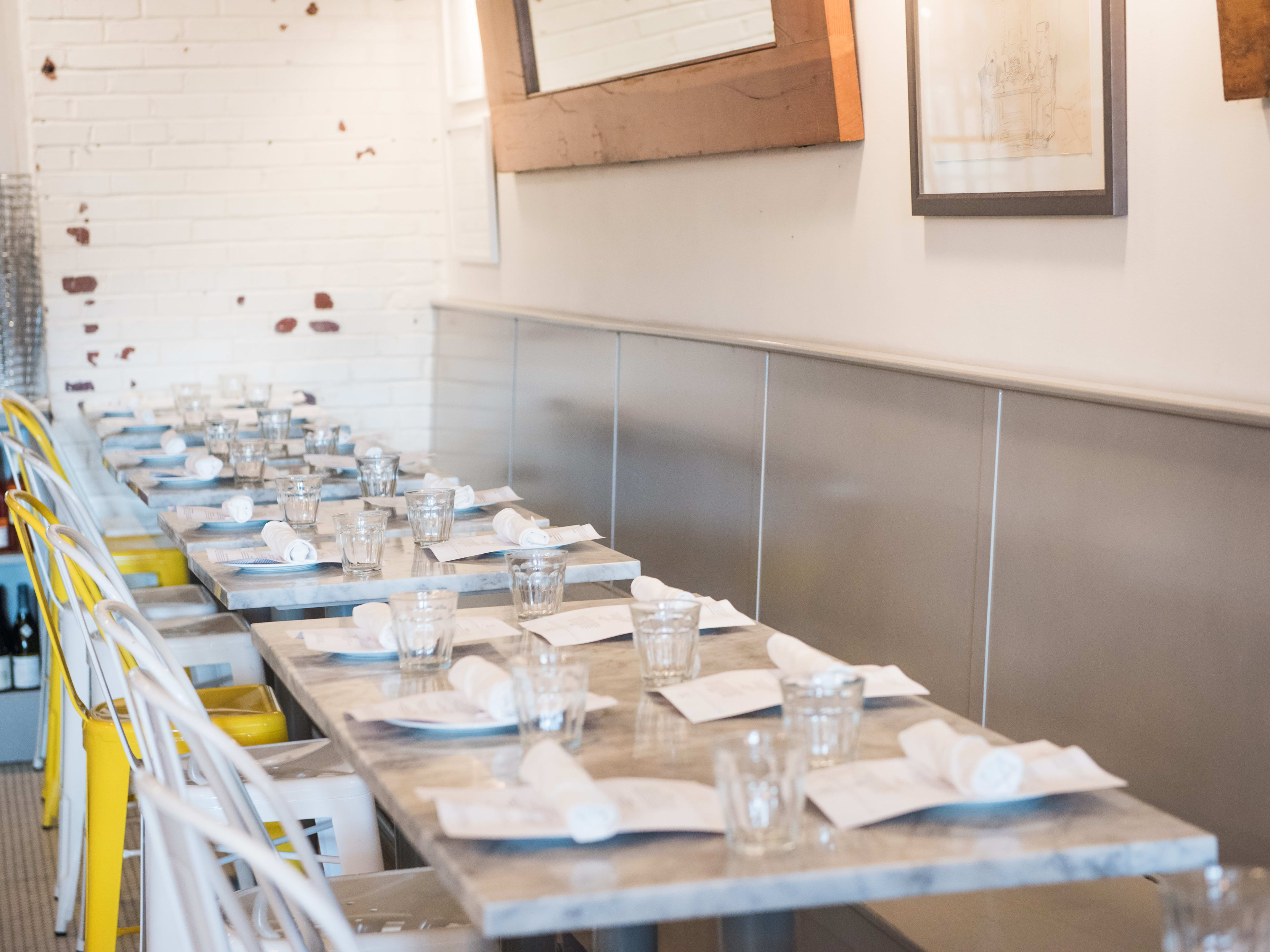 row of marble dining room tables with white and yellow chairs