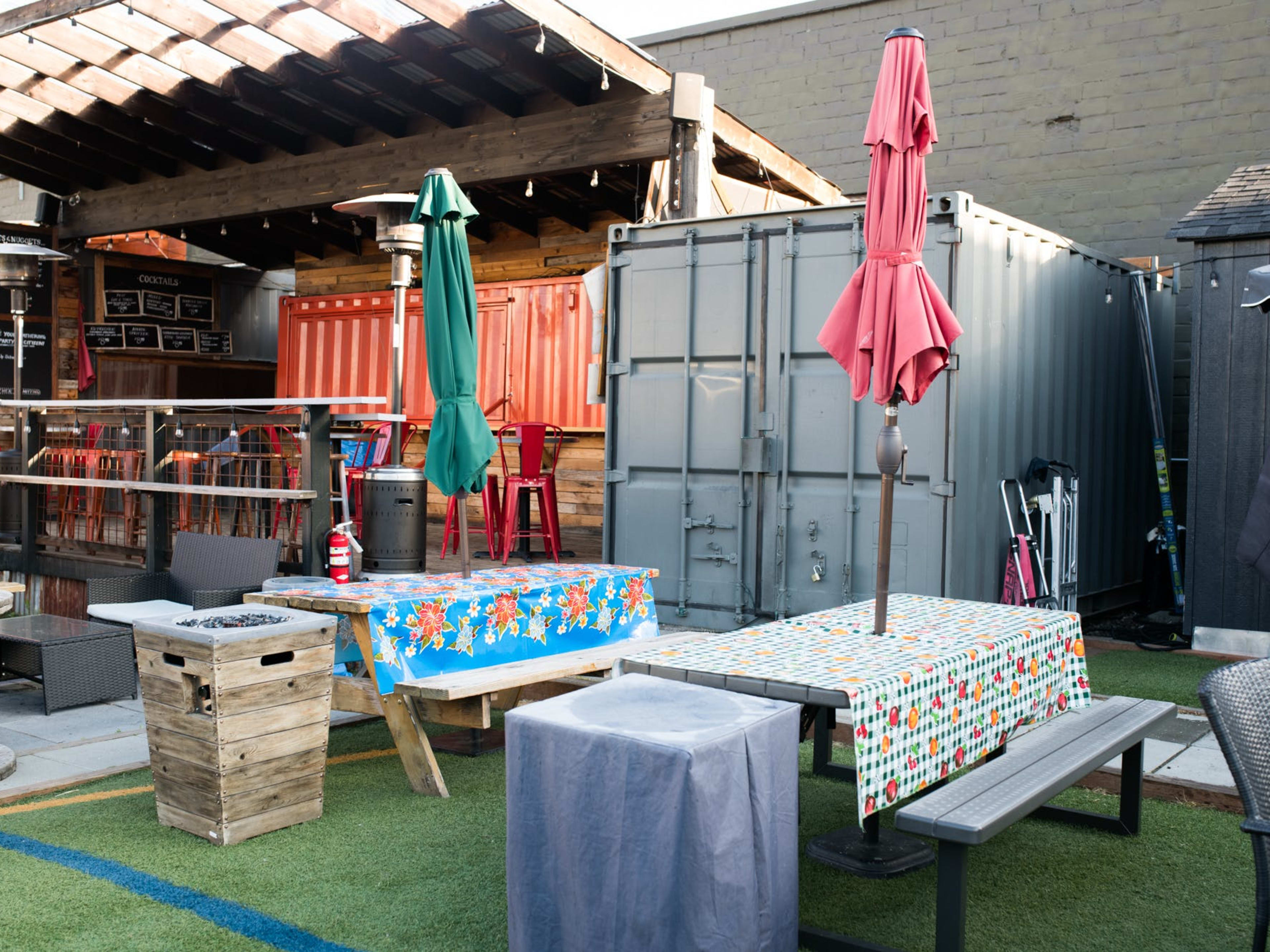 Patio bar with astroturf, decorated picnic tables, and umbrellas