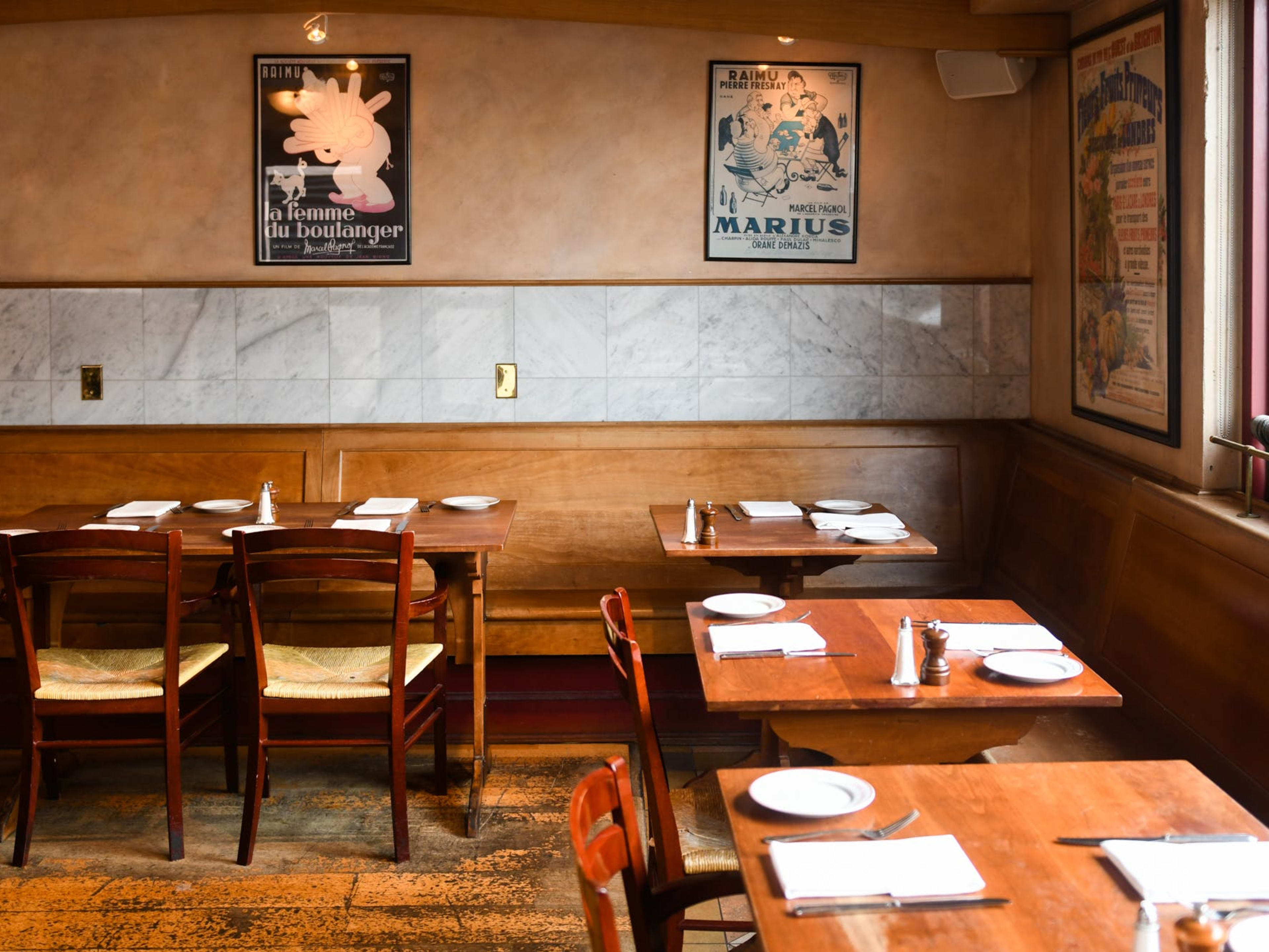 French dining room with posters, wooden tables, old wooden flooring, and marble tiling