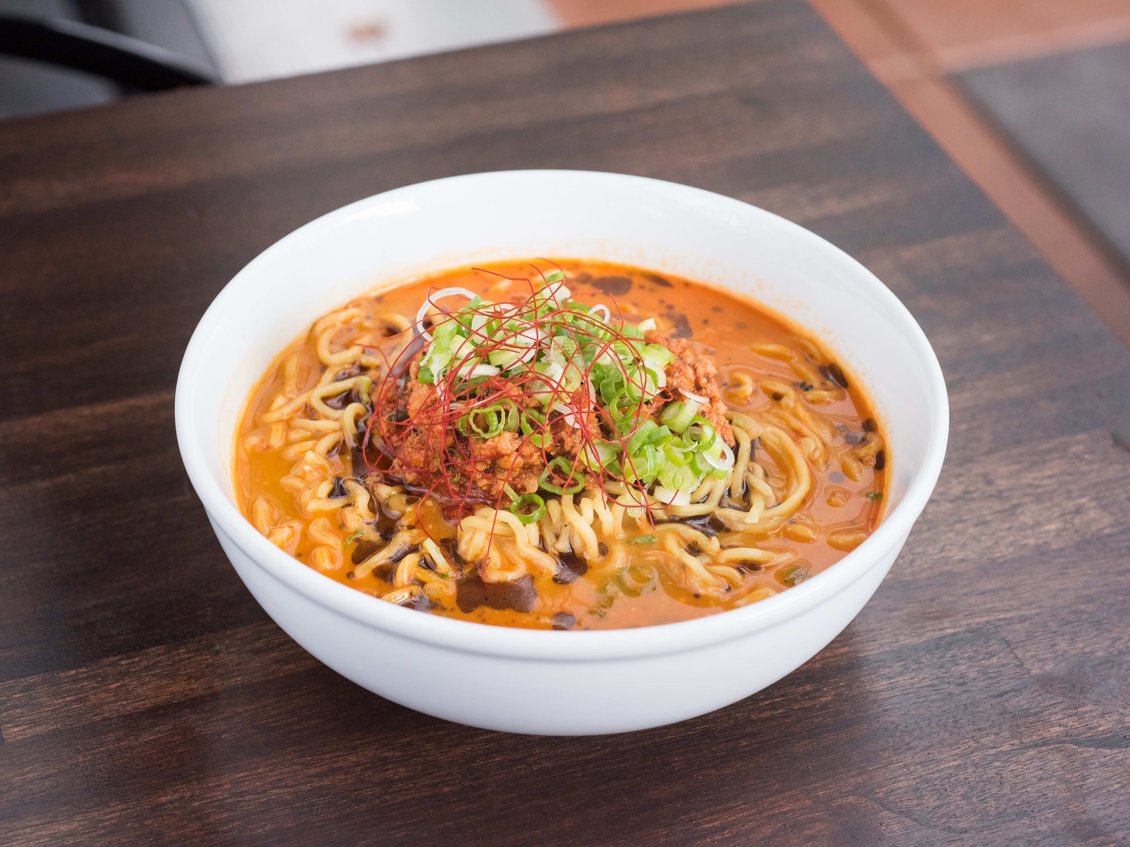 bowl of spicy dan dan ramen with scallions and chili threads.