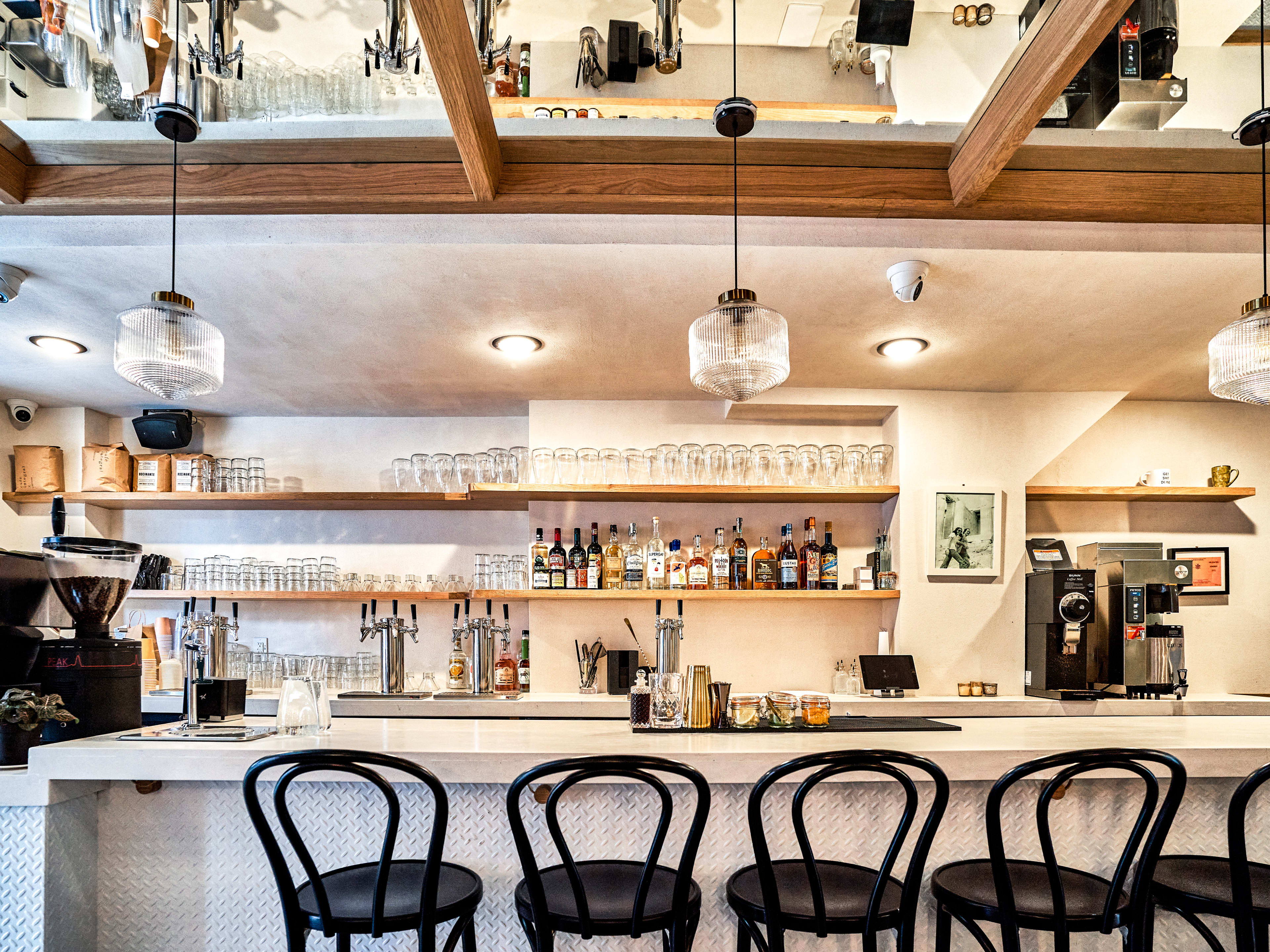 A bright restaurant with hanging lamps and a bar.