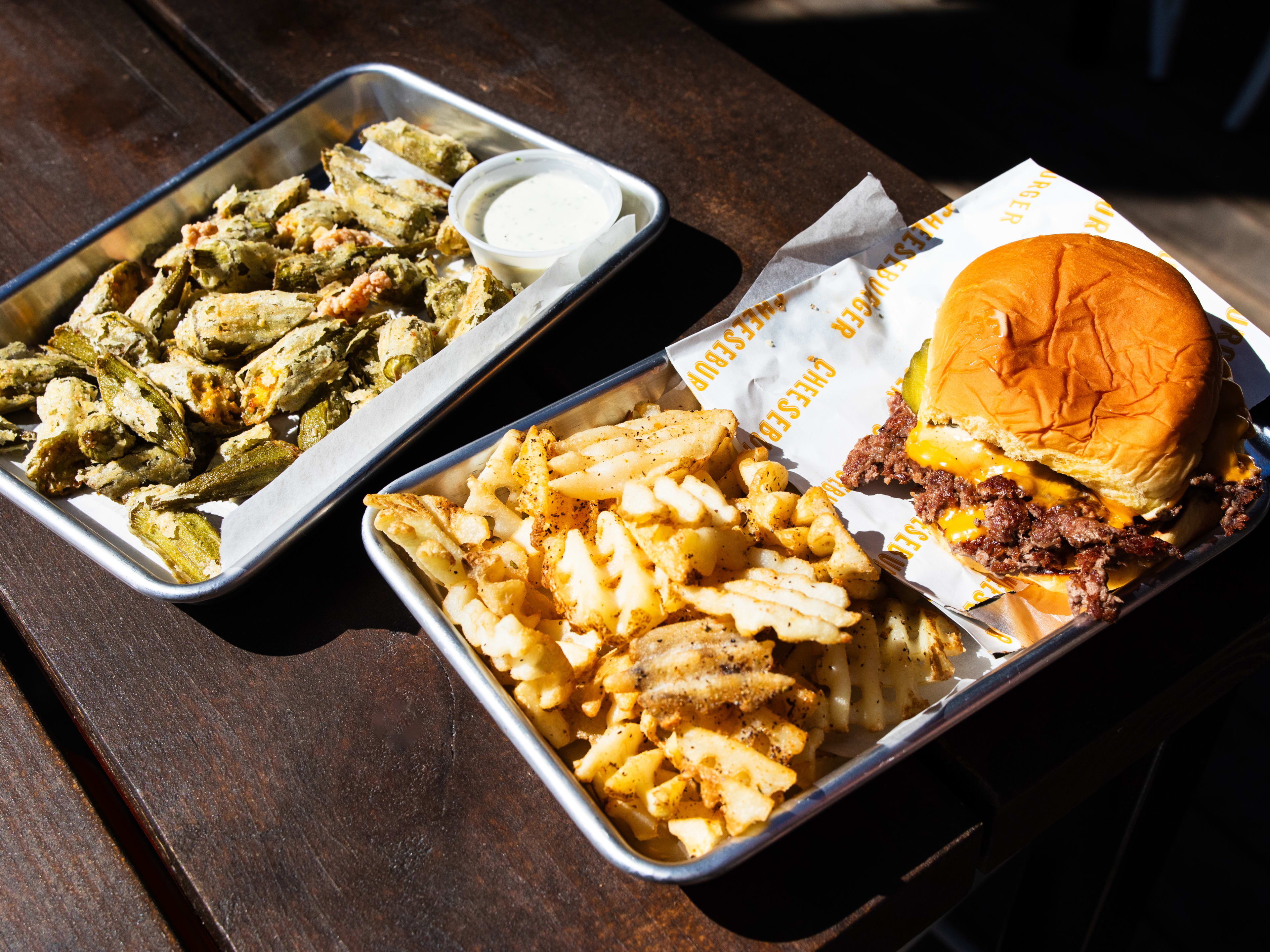 A smashburger and fries with a side of fried okrea