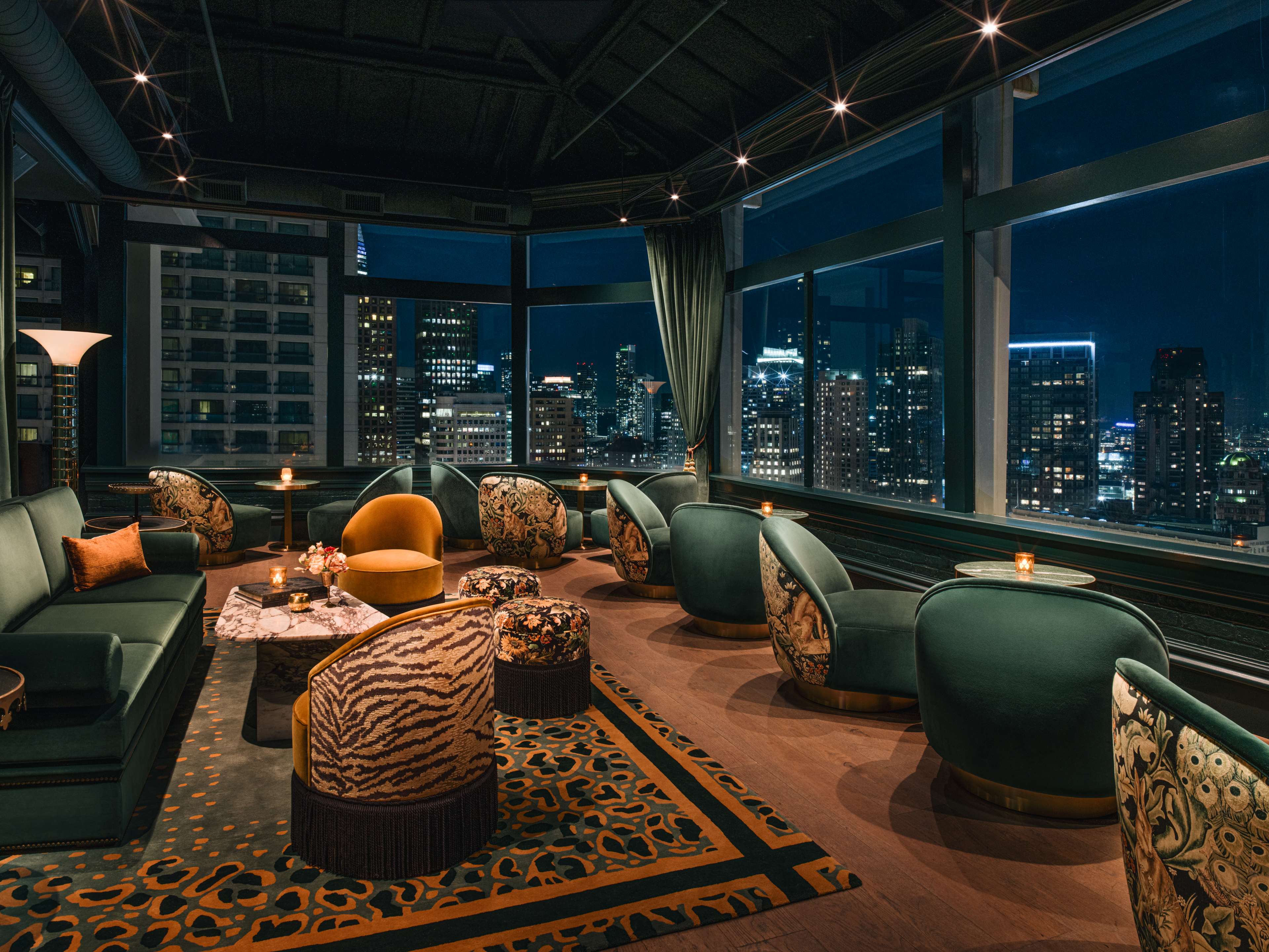 nighttime shot of 21st floor bar with velvet furniture and views of lit up San Francisco