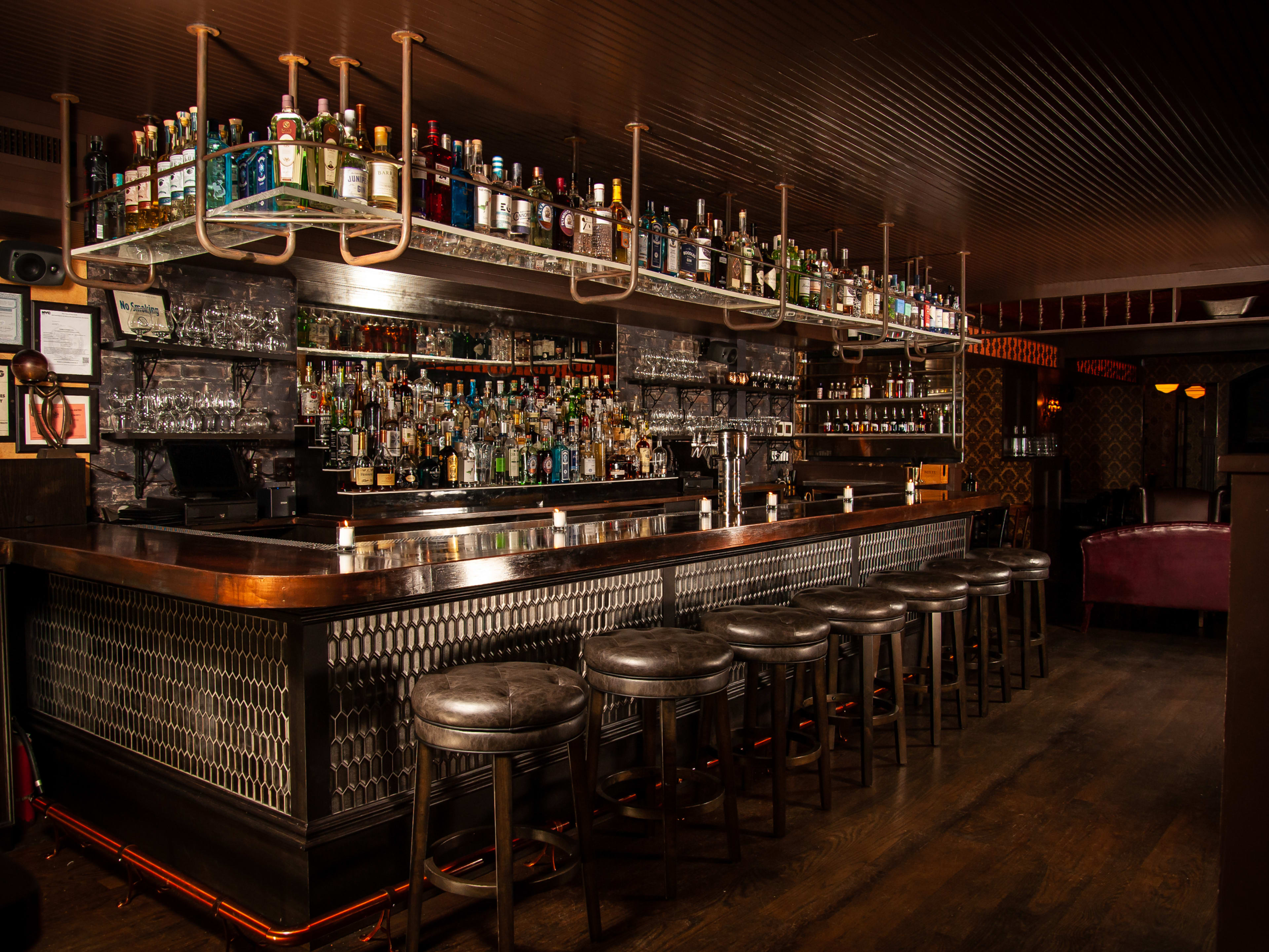 An upscale bar lined with bar stools in a dark, 1920s-themed room.