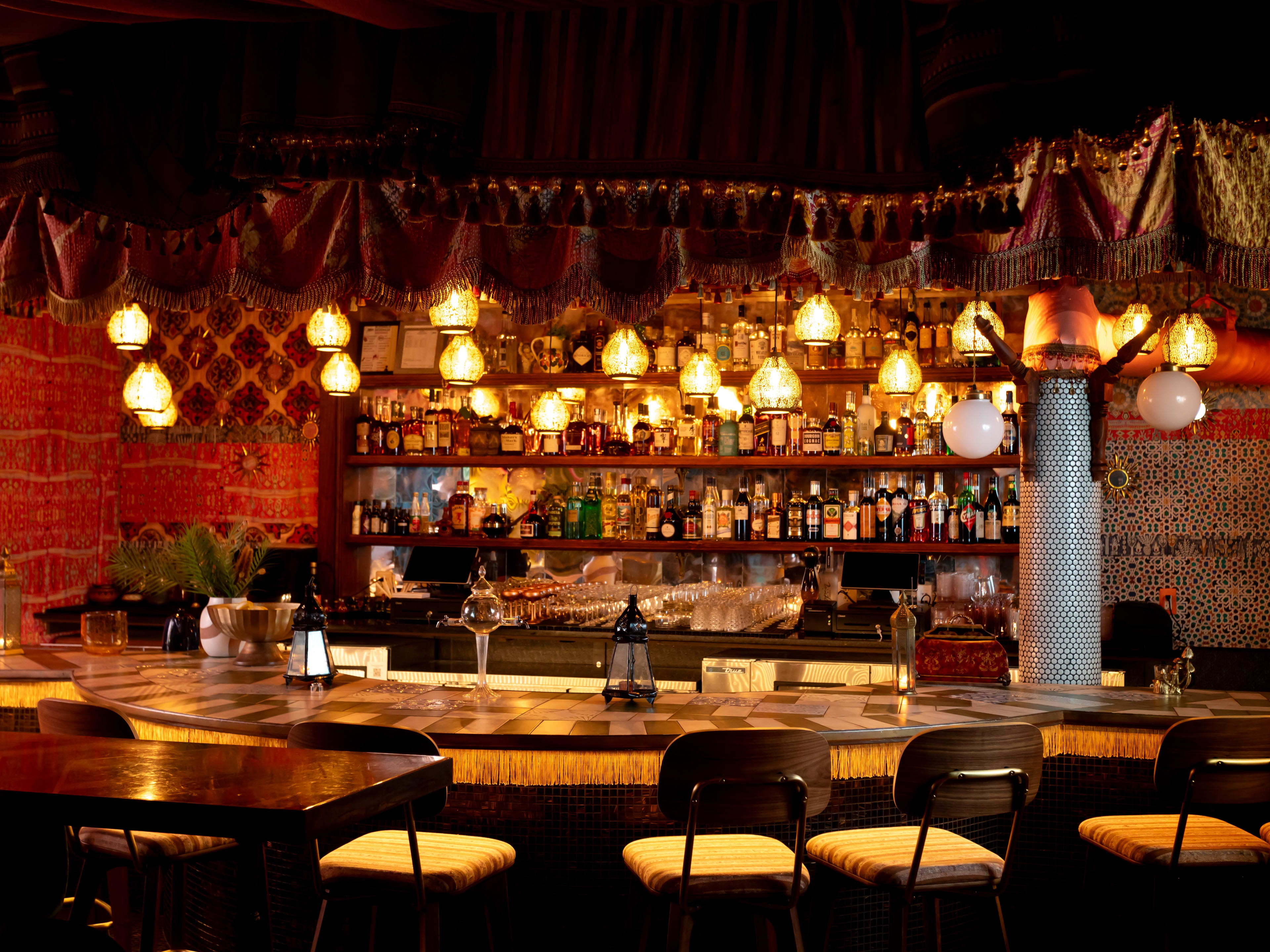 Warmly lit bar with fabric on ceiling and walls tent-style