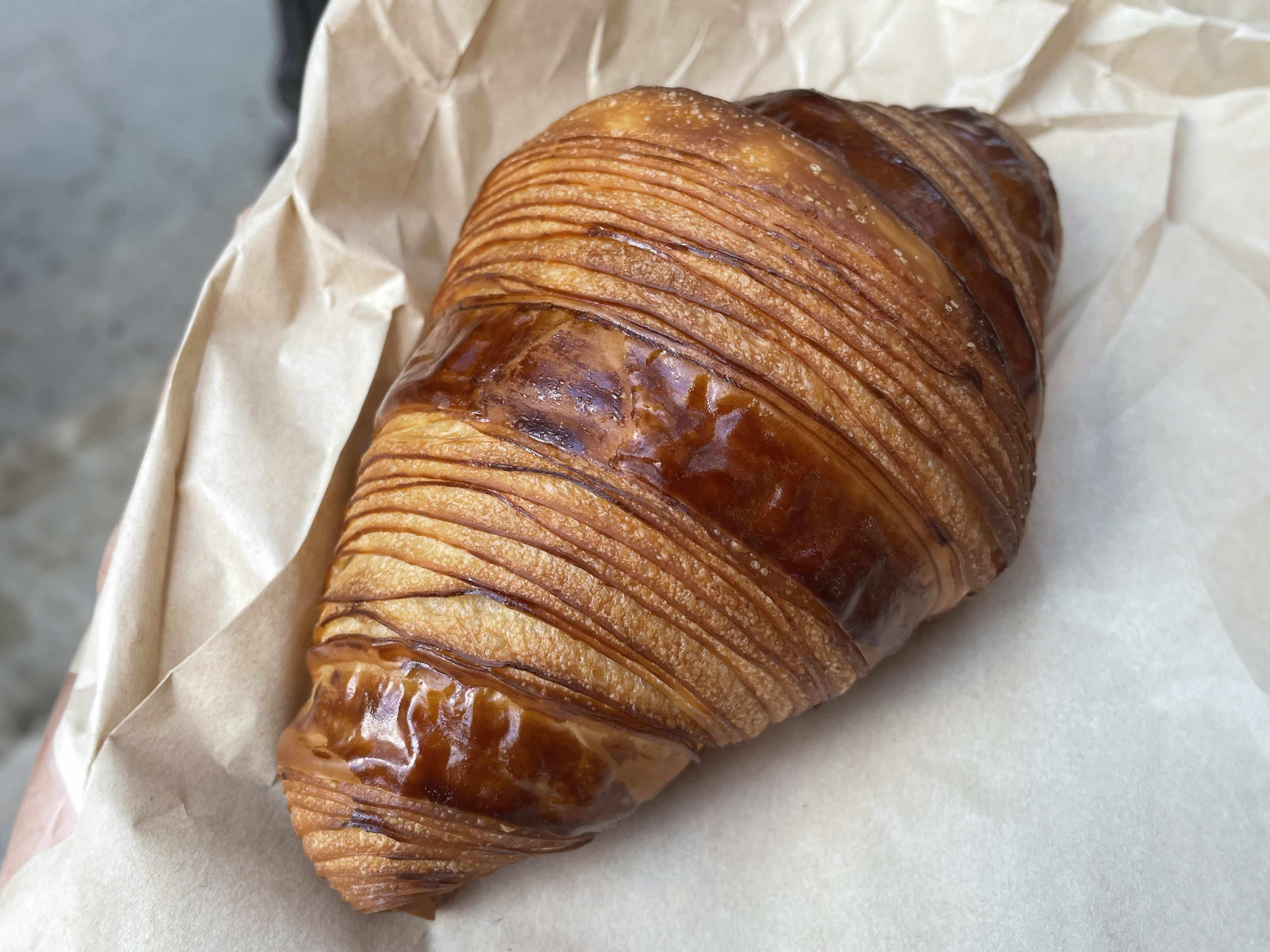 A croissant on a brown pastry bag.