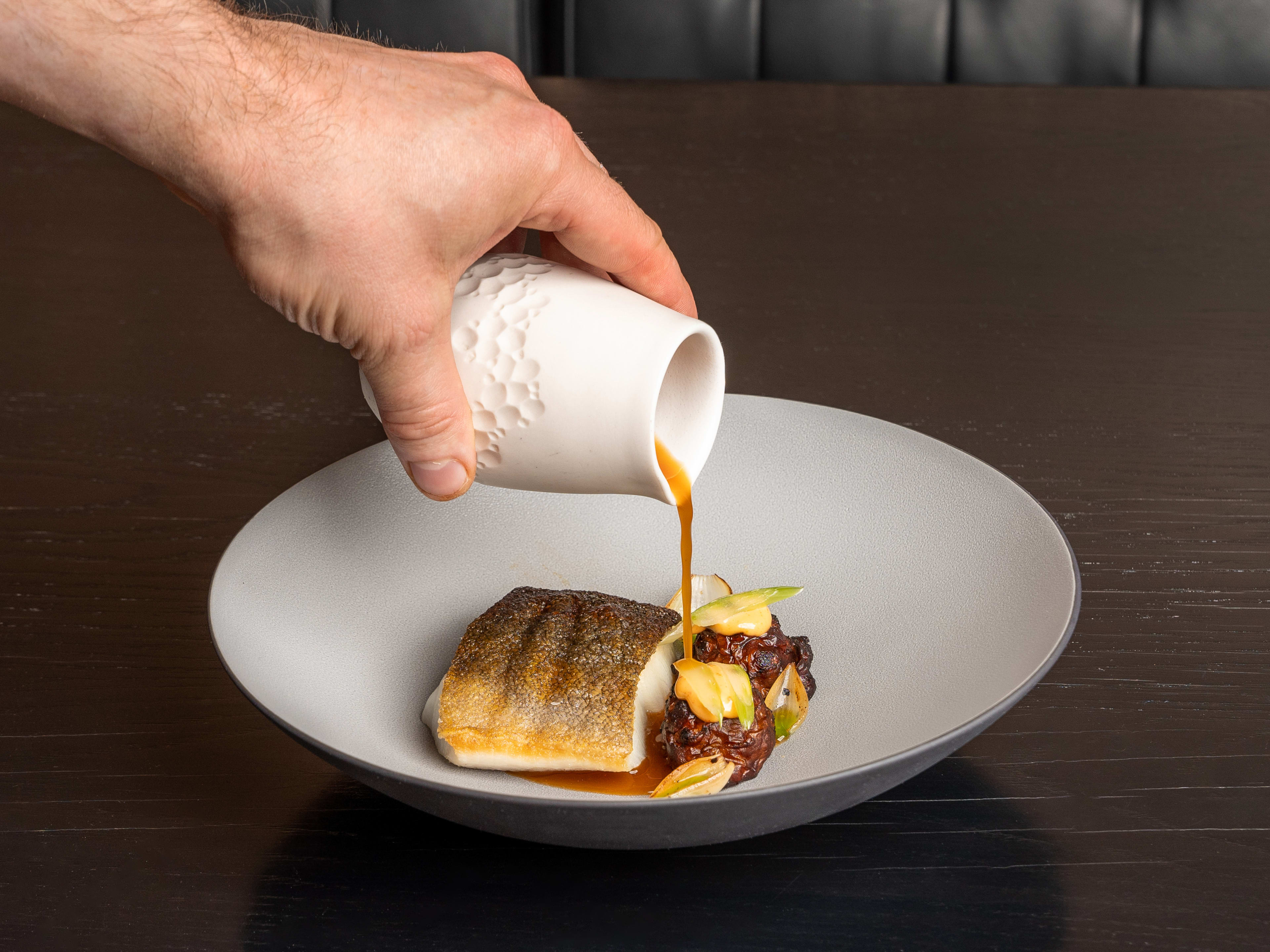 Staff pours broth over the black cod at 7 Adams