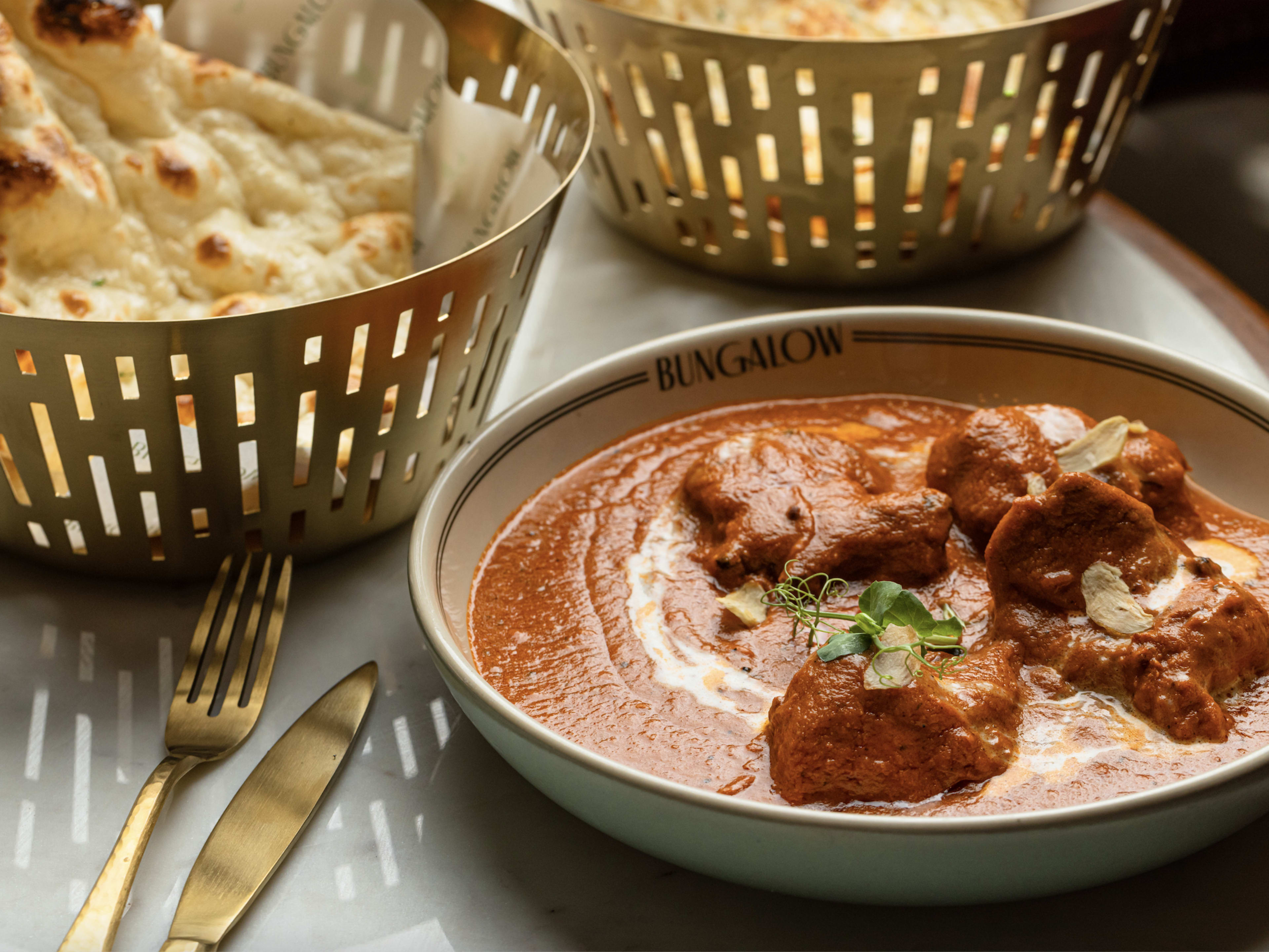 Chicken in a thick orange curry with a side of naan.