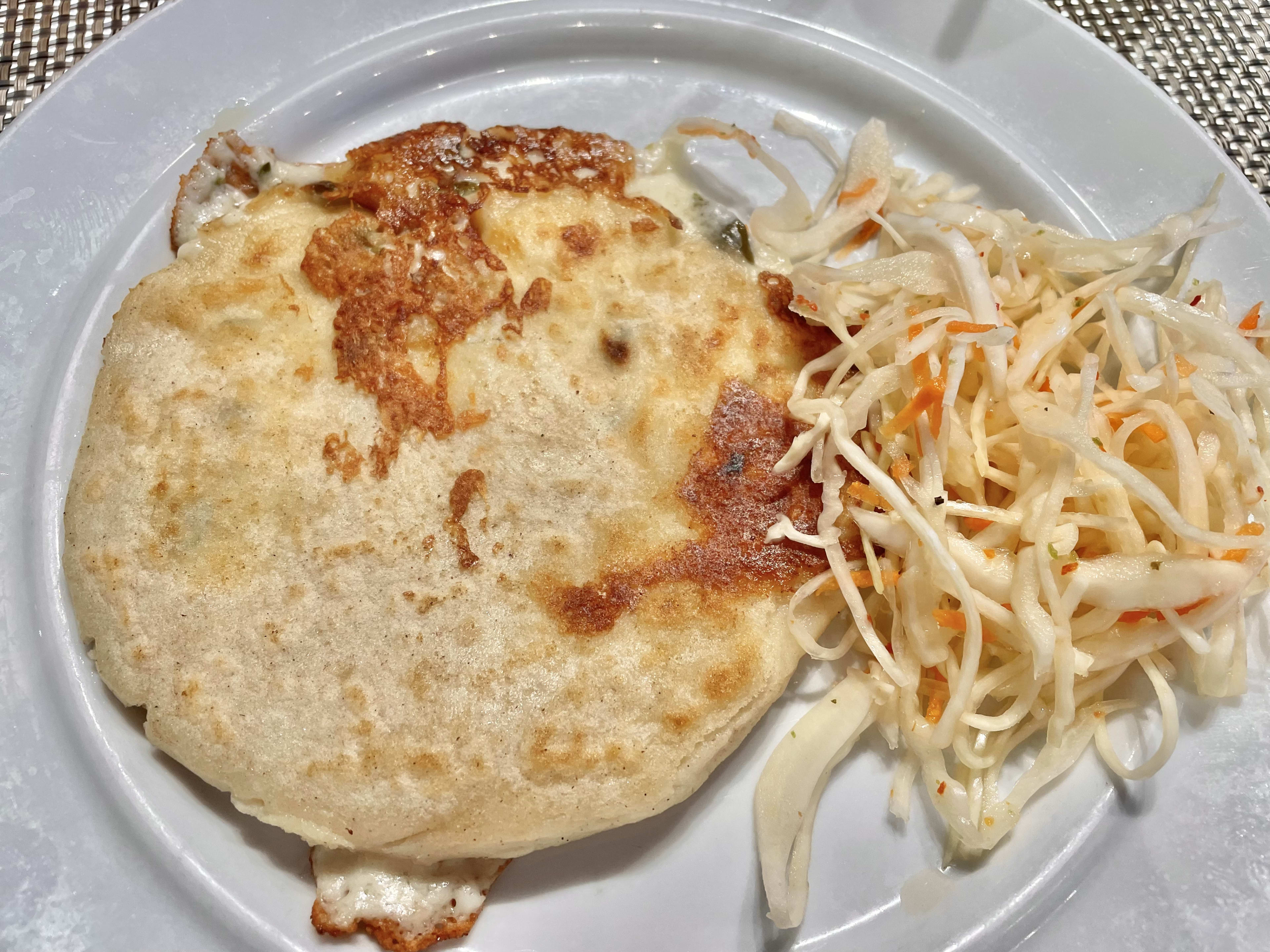 Pupusa with cheese and green flower stuffing and a side of cabbage