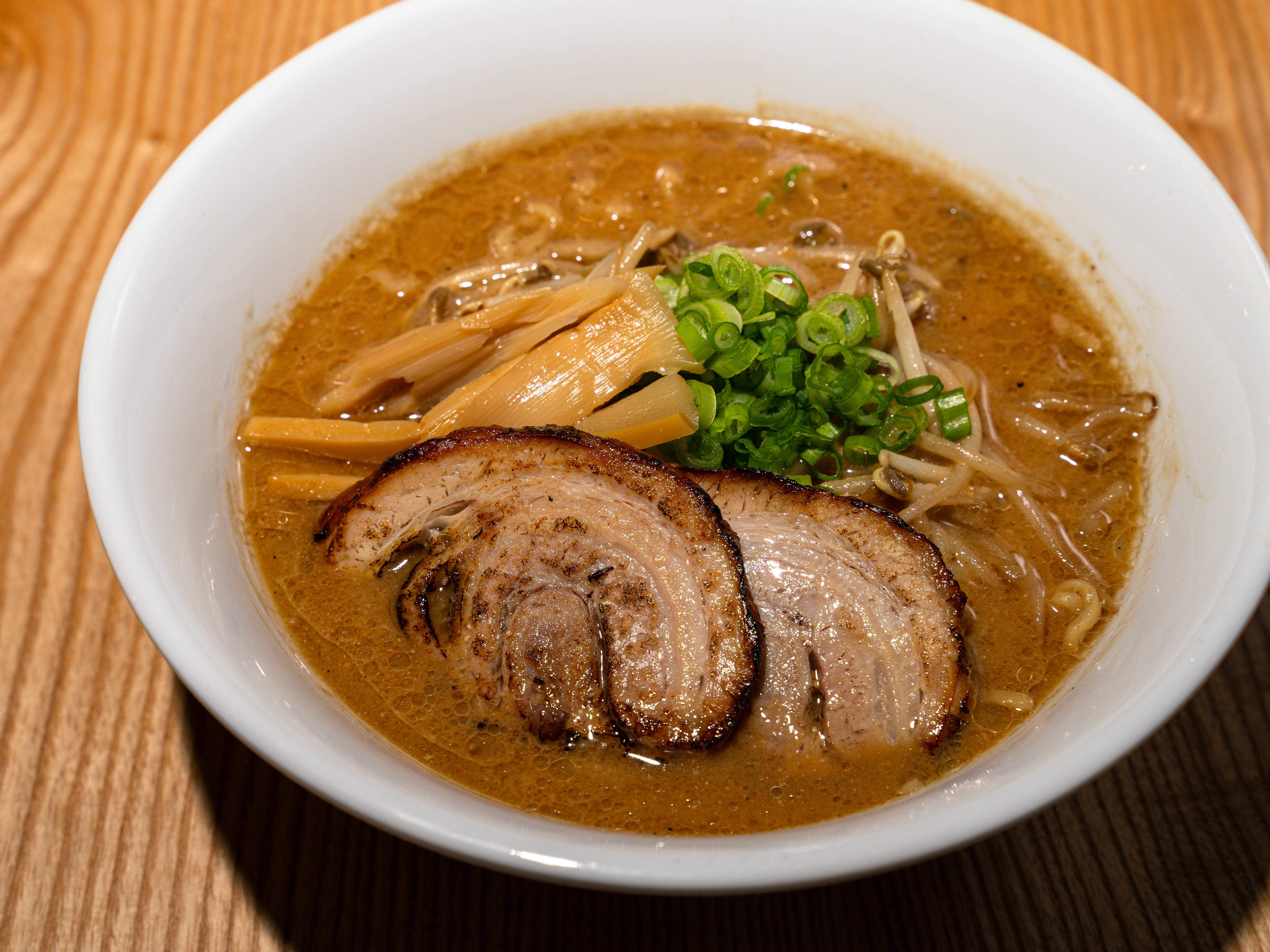 A bowl of miso ramen with pork chachu, bamboo shoots, and green onions.