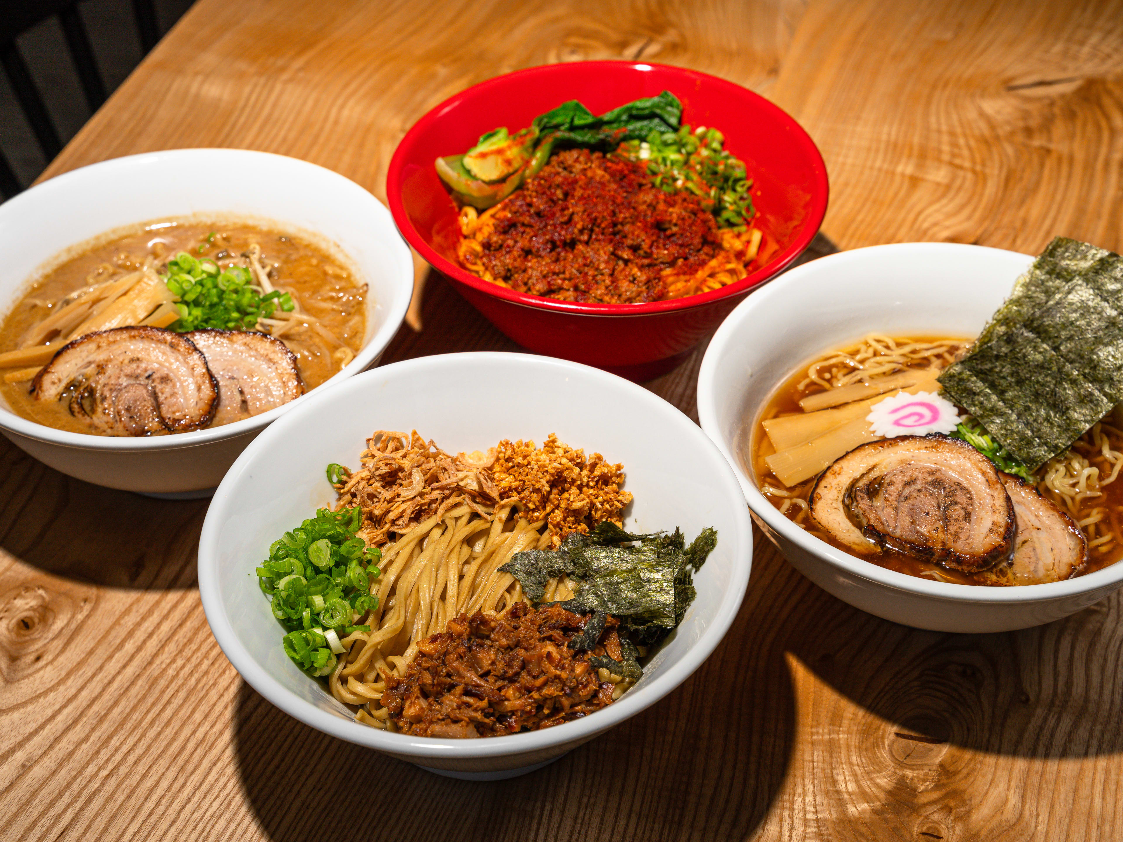 Four bowls of ramen on a wooden table.