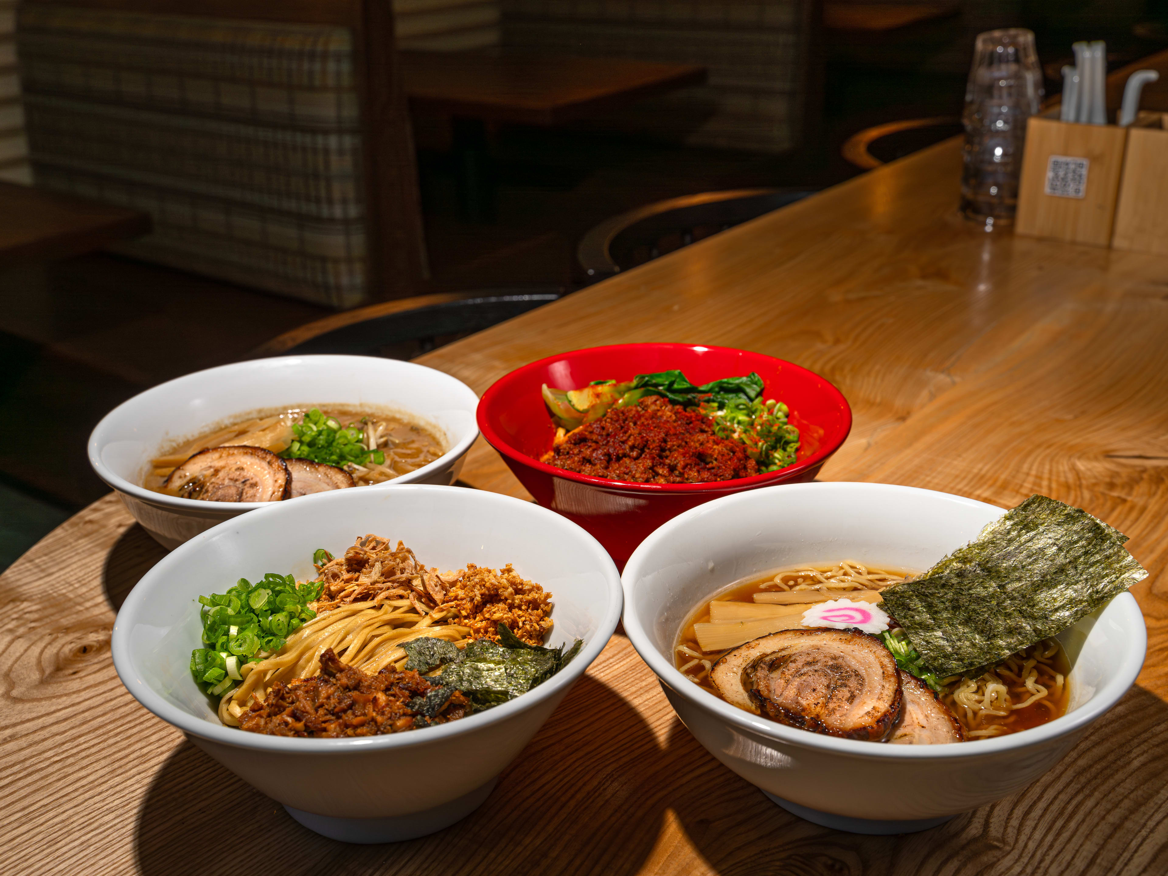 Four bowls of ramen on a wooden table.